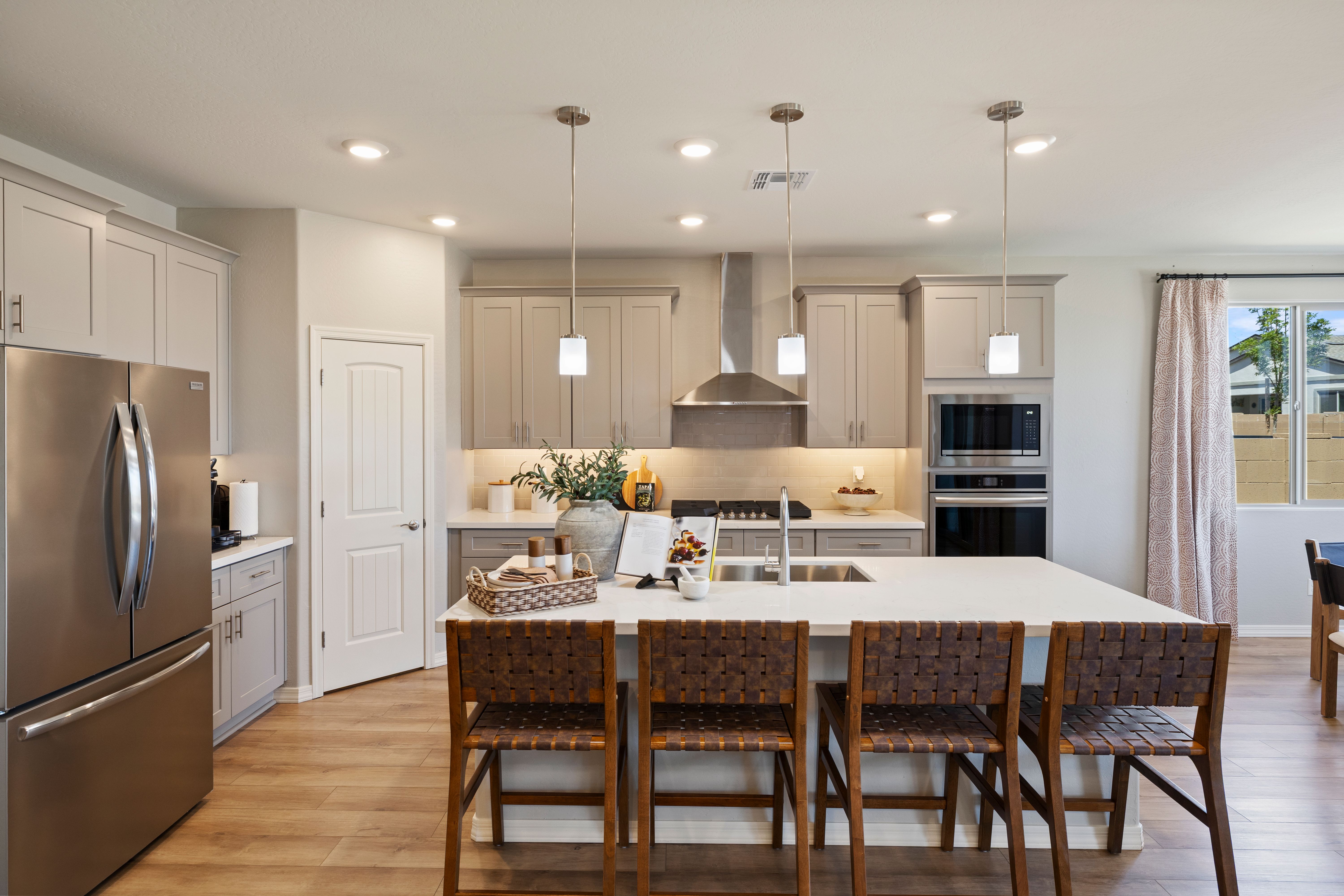 Spacious modern kitchen at North Ridge Pronghorn Ranch in Prescott Valley AZ with white cabinets quartz island bar stools and stainless appliances