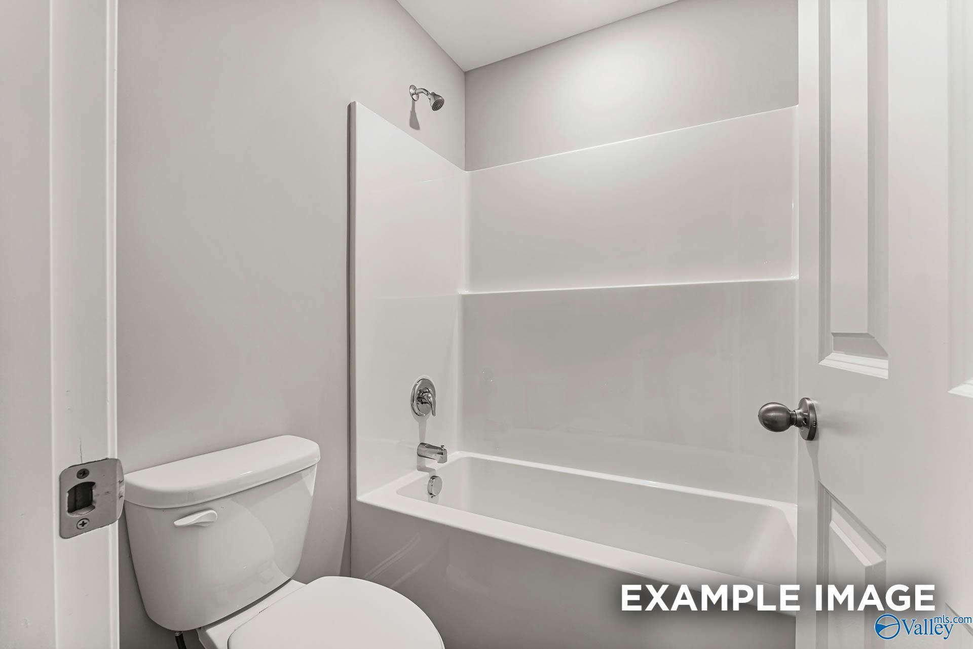 Modern white bathtub-shower combo with chrome fixtures and adjacent toilet in Davidson Homes Chelsea B bathroom, Toney, Alabama