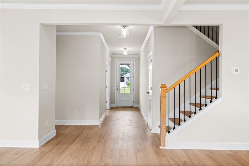 Bright entry foyer with hardwood floors, oak staircase, black balusters, and glass door in Davidson Homes The Hickory B at Wehunt Meadows, Hoschton