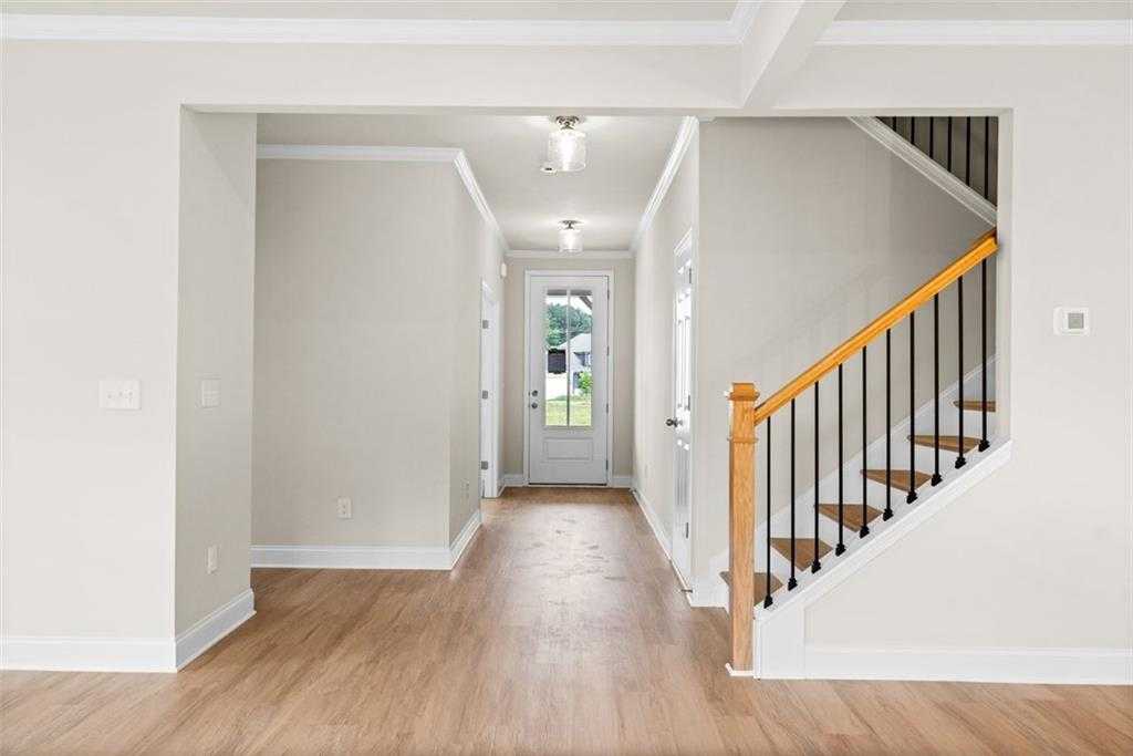 Bright entry foyer with hardwood floors, oak staircase, black balusters, and glass door in Davidson Homes The Hickory B at Wehunt Meadows, Hoschton