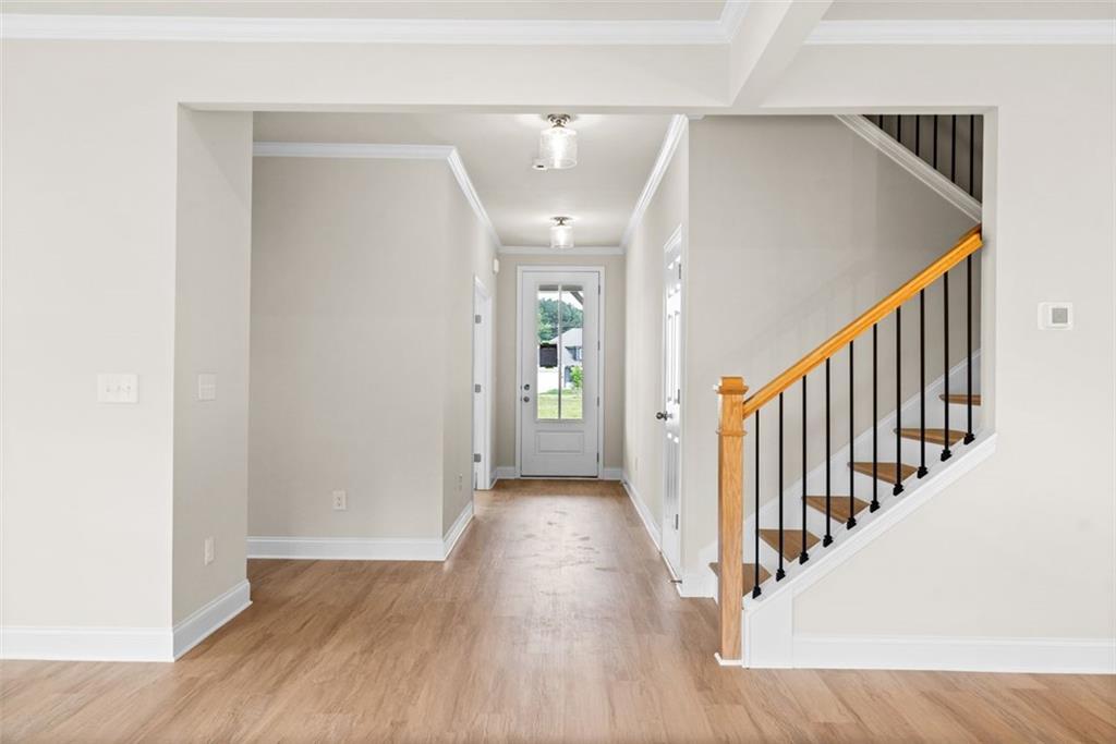 Bright entry foyer with hardwood floors, oak staircase, black balusters, and glass door in Davidson Homes The Hickory B at Wehunt Meadows, Hoschton