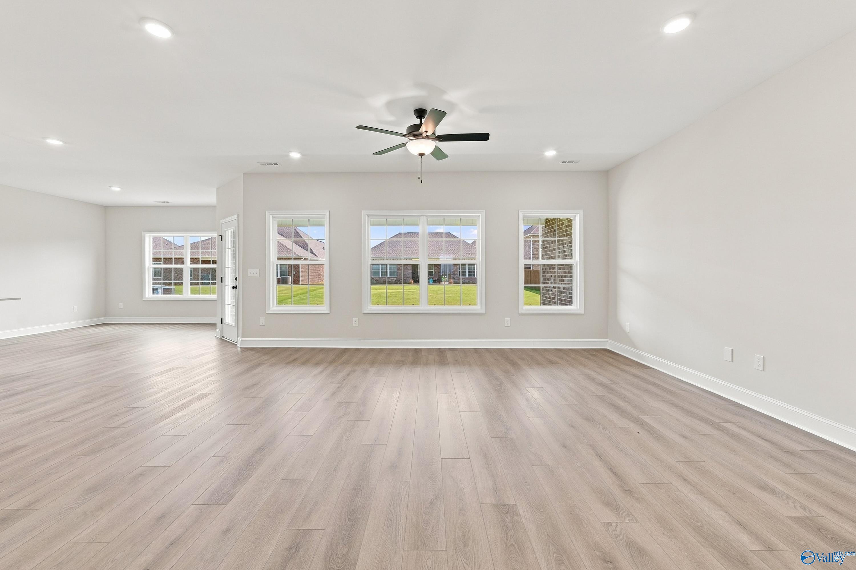 Spacious, open-concept living area with wood-look flooring in The Rockford B floor plan at Kendall Downs, Toney, Alabama.