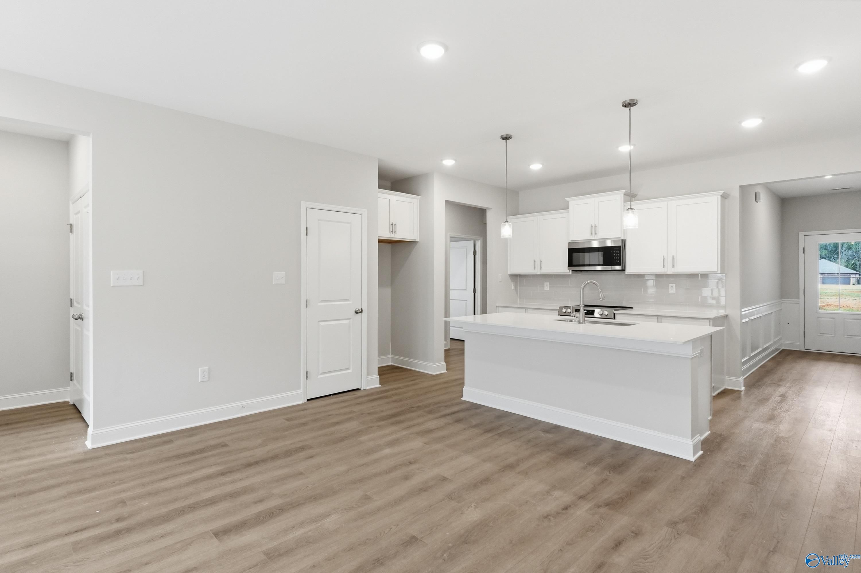 Modern open kitchen with white island, cabinets, stainless microwave in The Cumberland 3-bedroom home, Decatur AL