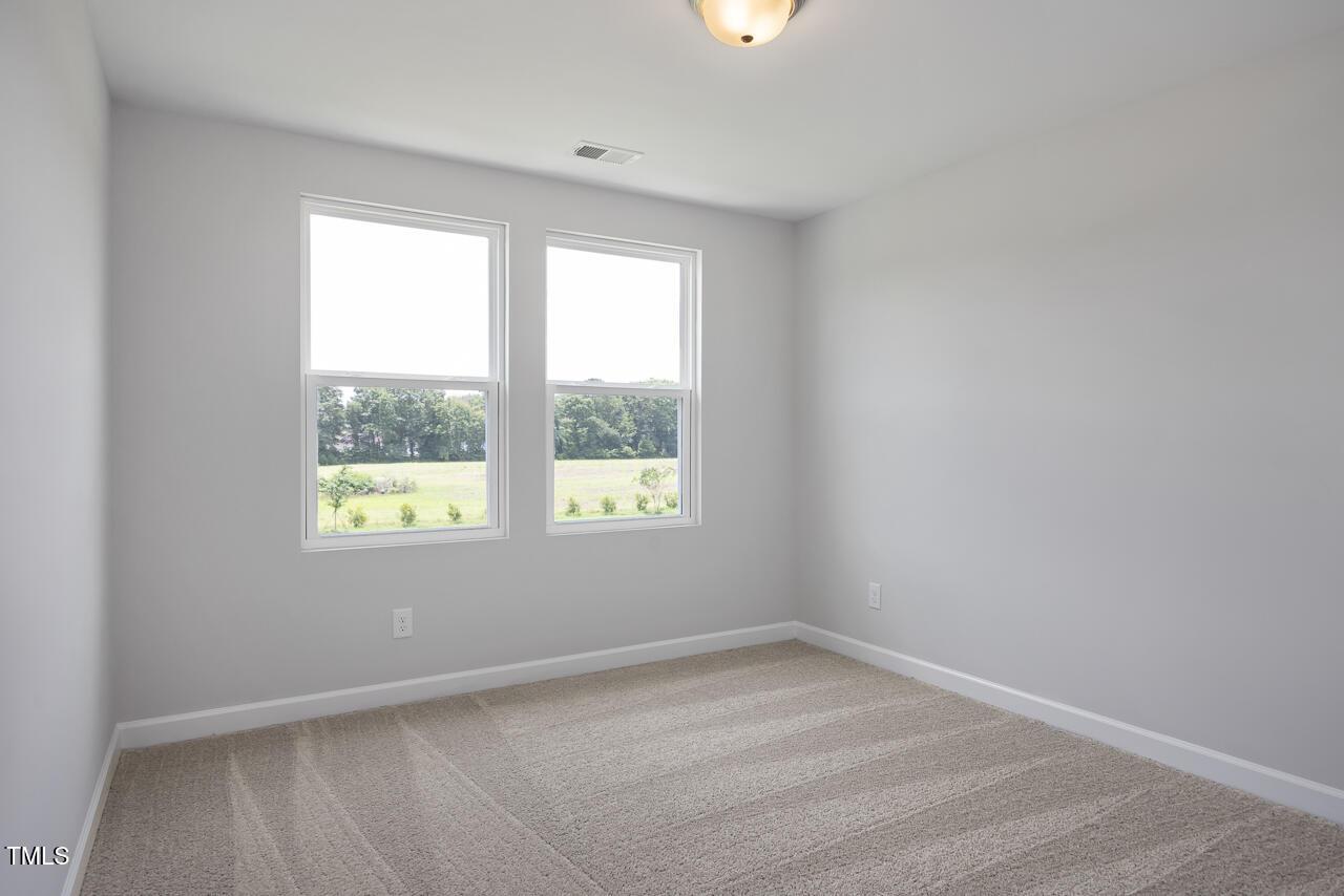 Bright secondary bedroom with large windows and green yard view in Davidson Homes The Warren, Fuquay-Varina, NC