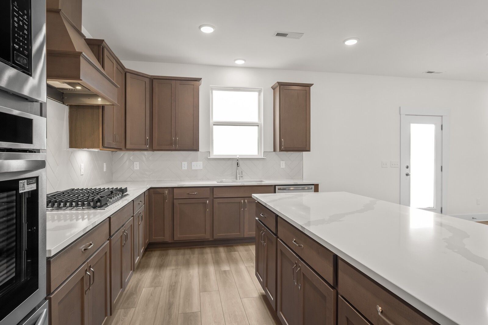 Modern kitchen with quartz island, wood cabinets, and stainless steel appliances in The Henry C floor plan, Mt. Juliet, TN.