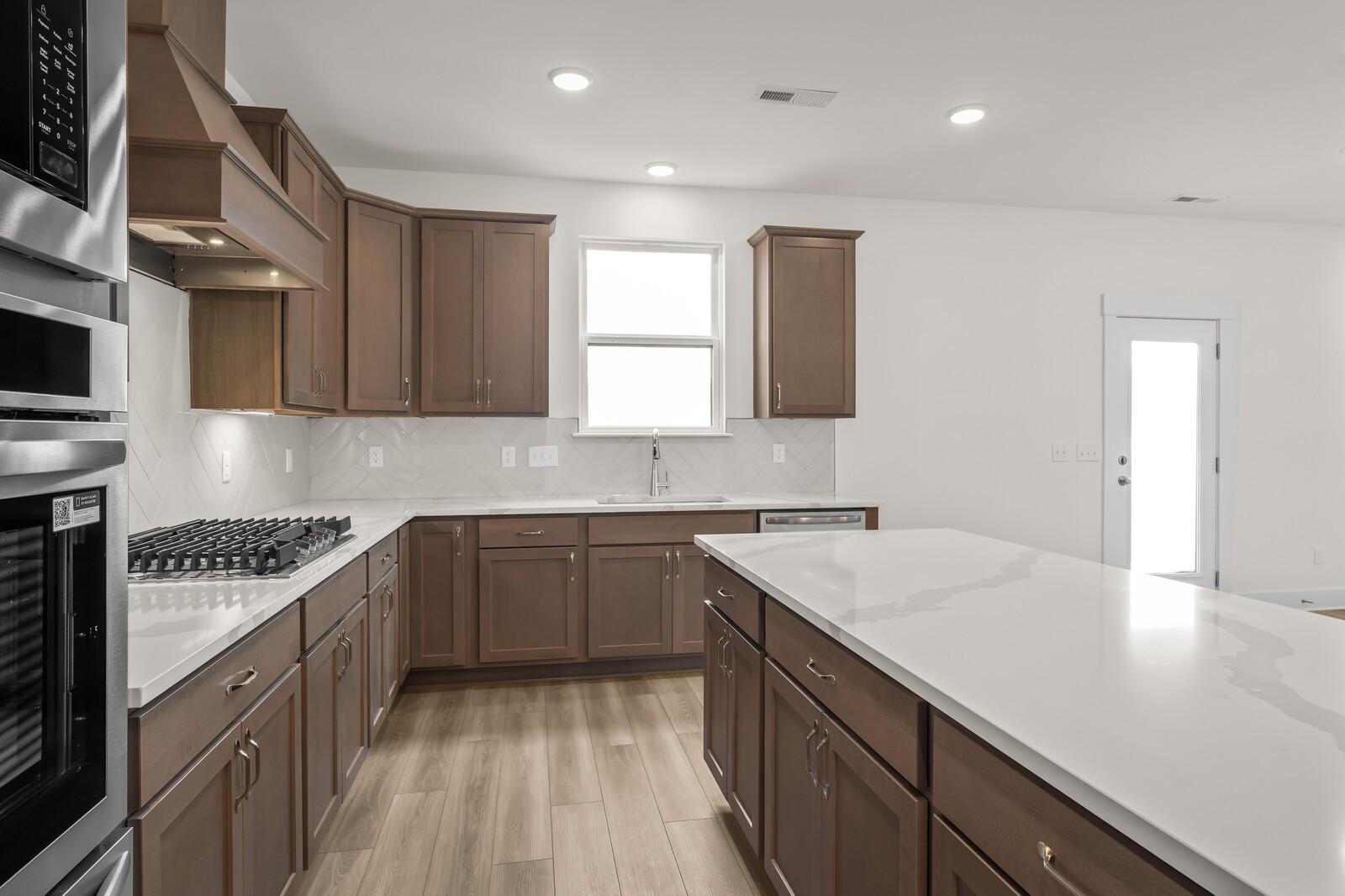Modern kitchen with quartz island, wood cabinets, and stainless steel appliances in The Henry C floor plan, Mt. Juliet, TN.