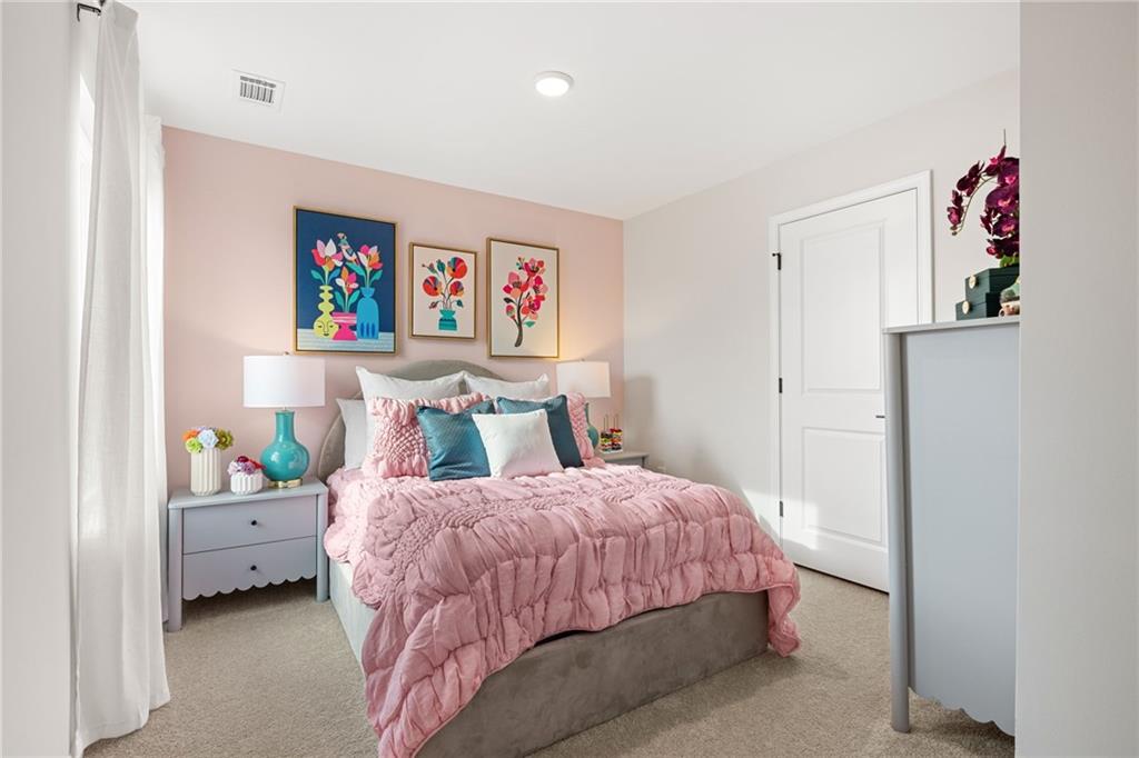 Charming pink bedroom with tufted bed, colorful pillows, floral art in Davidson Homes The Rabun B, Canton GA