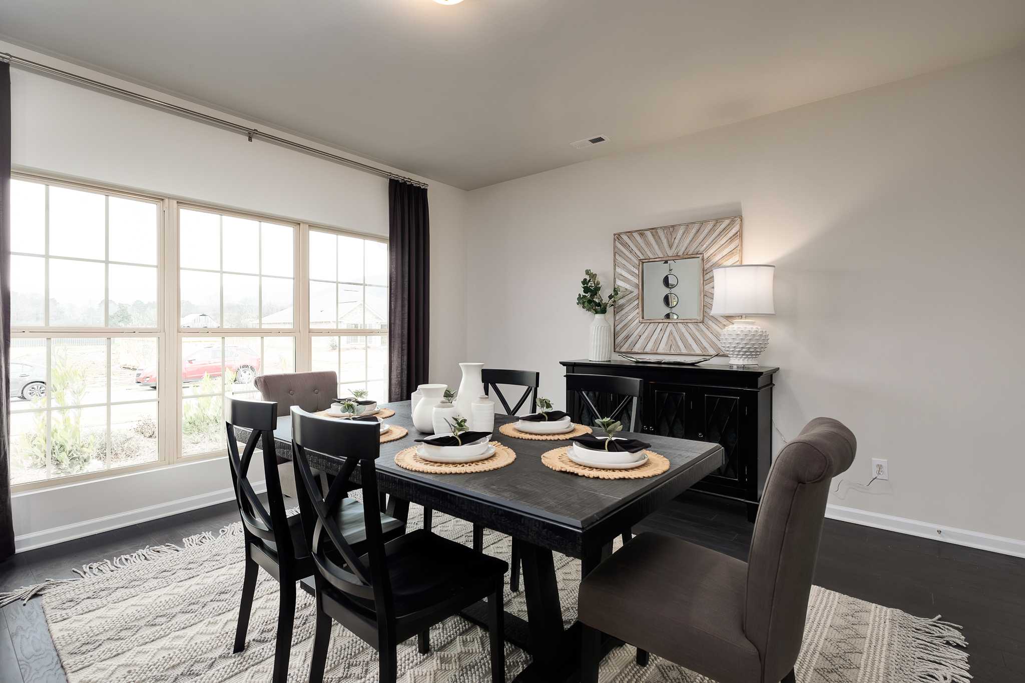 Spacious dining room at The Reserve at Overton in Hampton Cove, Alabama with black wood table, large windows, and neutral decor