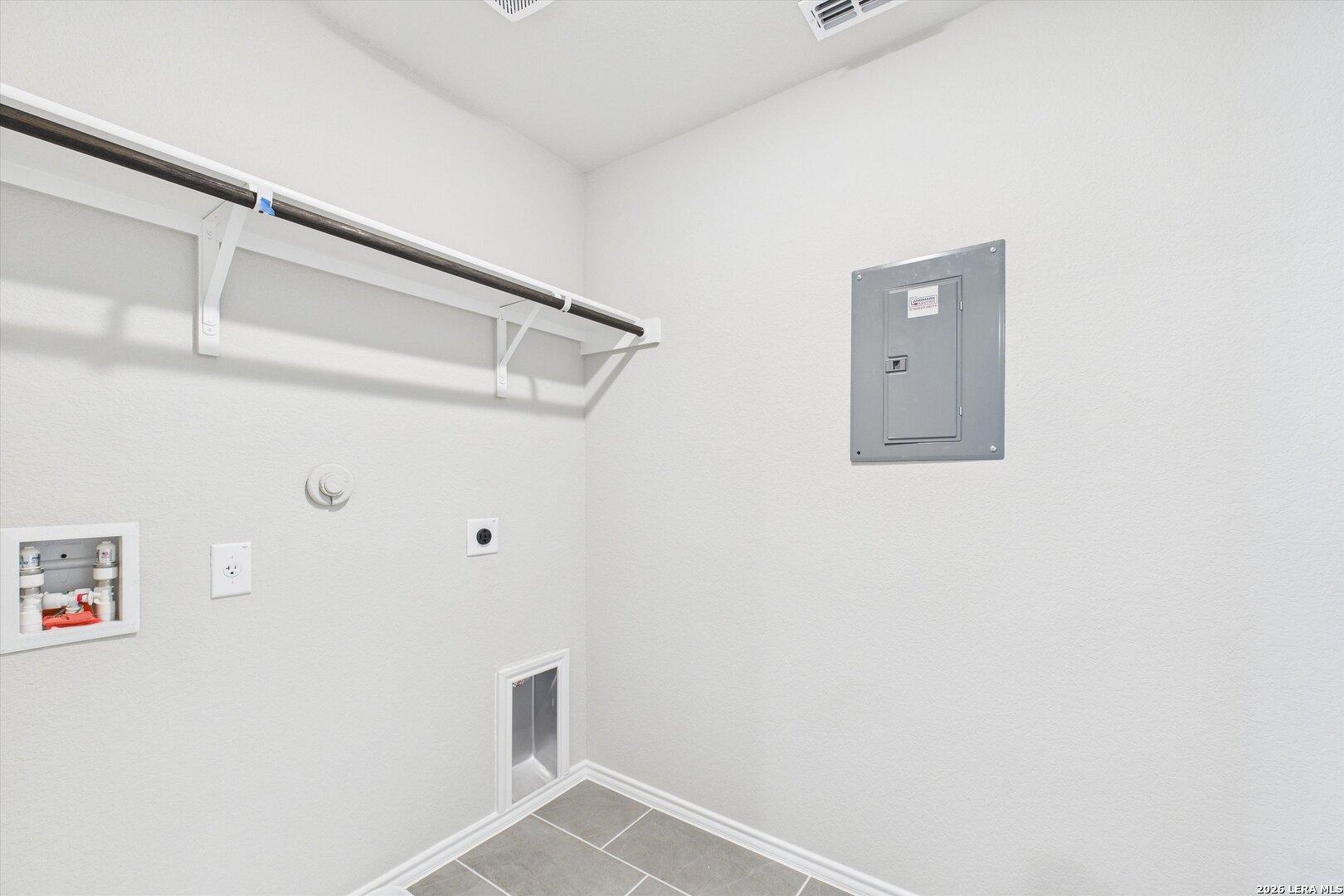 Bright laundry room with hanging rod, water heater, electrical panel, and pet door in Davidson Homes Charlotte A, San Antonio, Texas