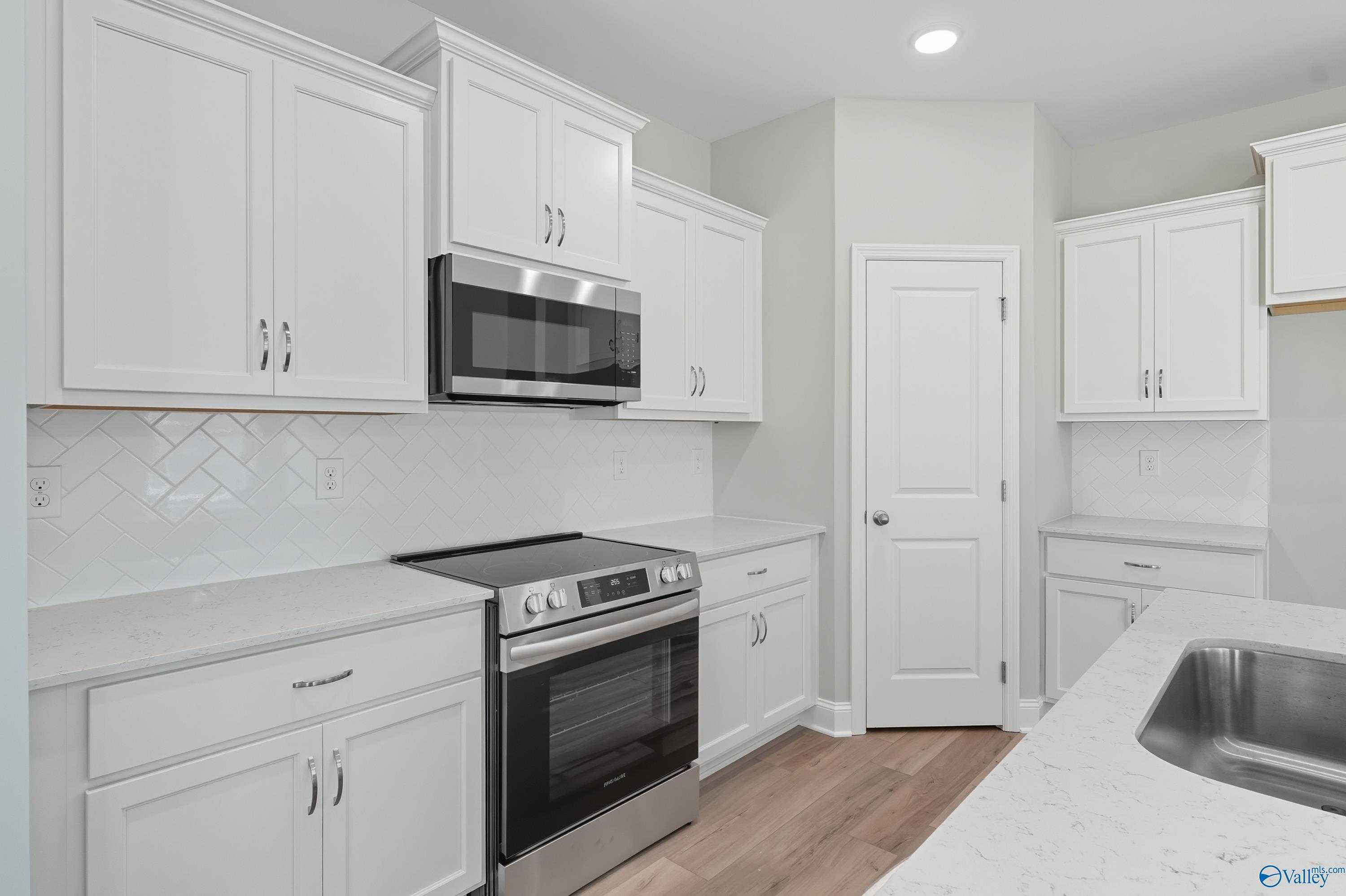Modern white kitchen with stainless steel appliances, quartz counters, subway tile backsplash in Davidson Homes The Franklin C, Meridianville, AL
