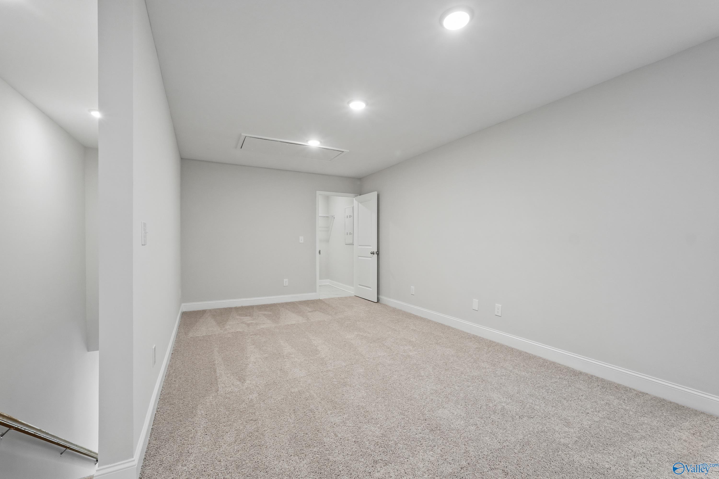 Empty bedroom with beige carpet, light gray walls, and bathroom door in Davidson Homes The Camden, Pavilion, Huntsville, Alabama
