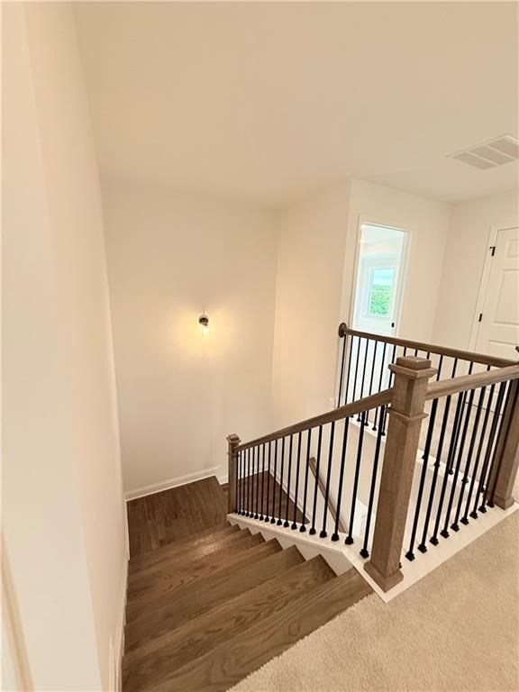 Staircase with wood treads and black iron railings in The Hickory B floor plan at Wehunt Meadows, Hoschton, Georgia.