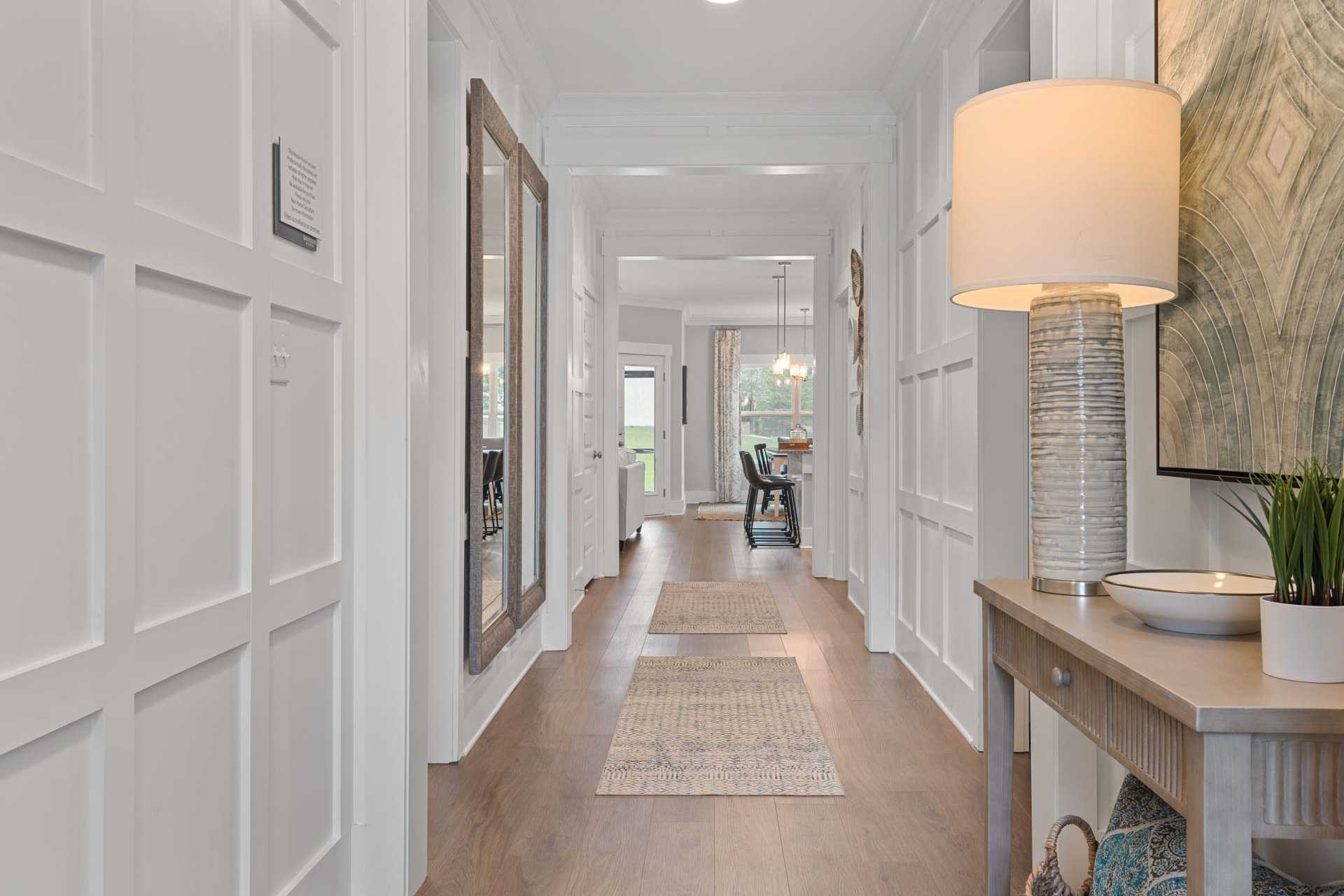 Spacious hallway in Monteagle Cove Owens Cross Roads AL home with white wainscoting, hardwood floors, console table lamp