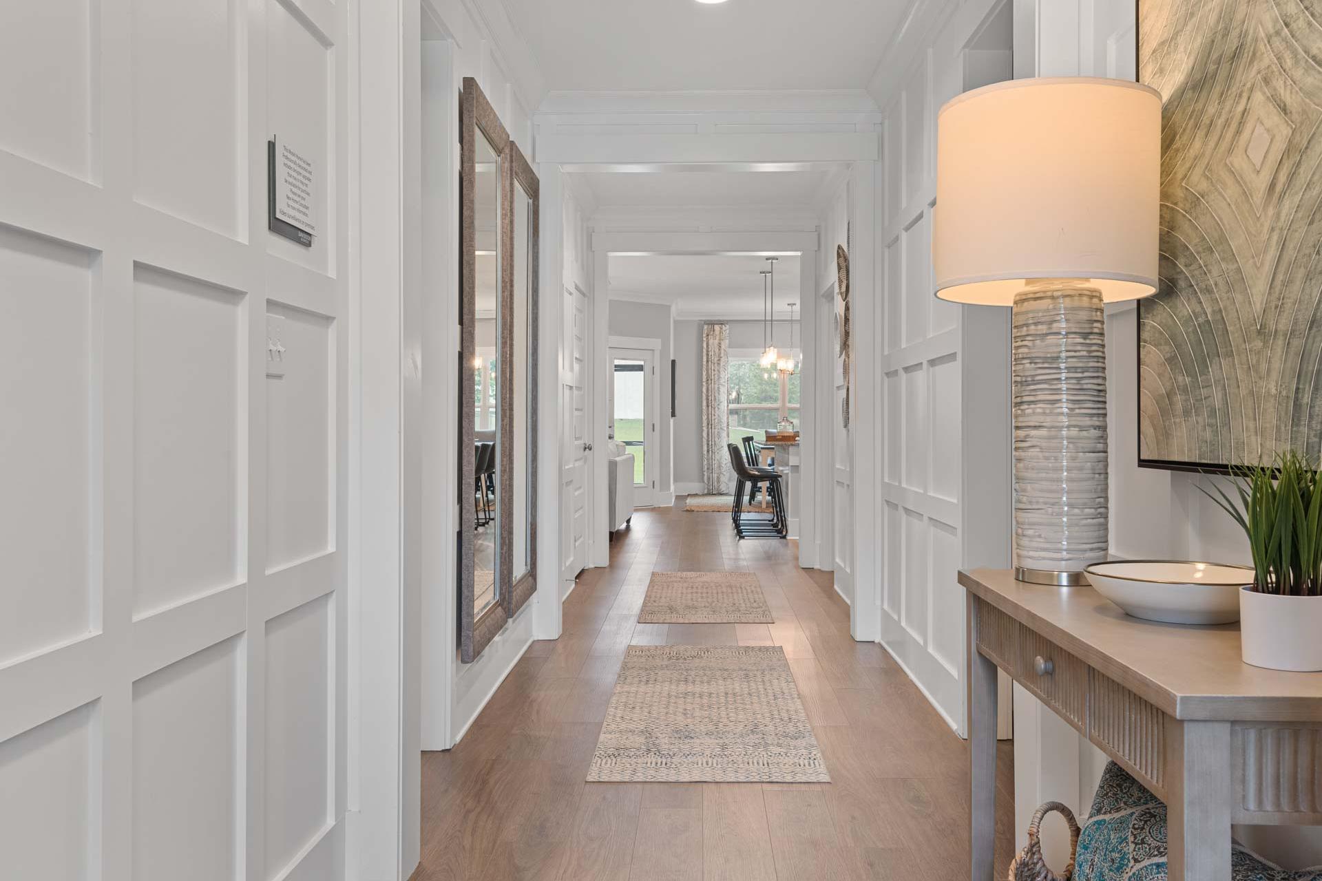 Spacious hallway in Monteagle Cove Owens Cross Roads AL home with white wainscoting, hardwood floors, console table lamp