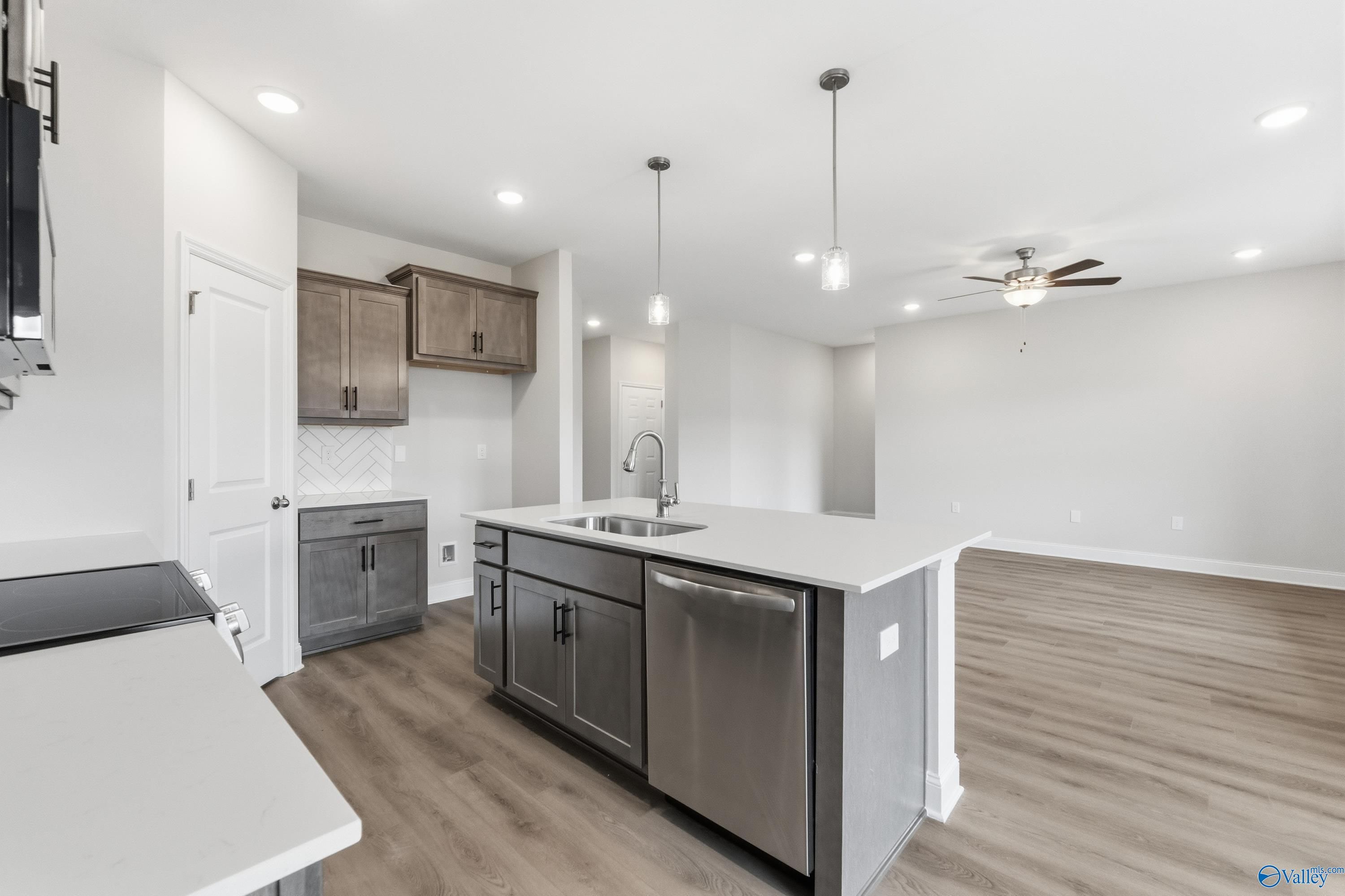 Modern open-concept kitchen with white shaker cabinets, gray island sink, stainless appliances in The Asheville C, Davidson Homes, Huntsville AL