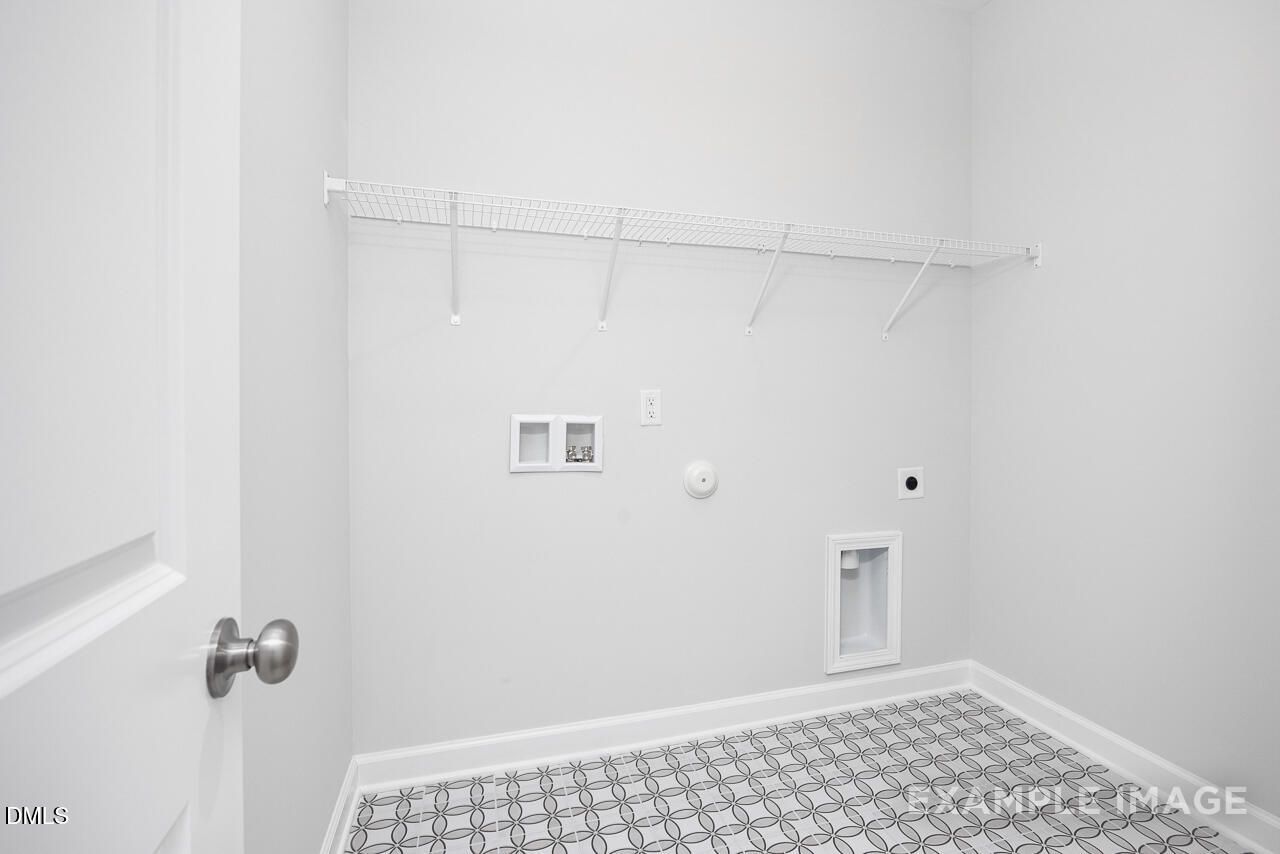 Modern laundry room with white hanging rod, washer dryer hookups, checkered tile floor in The Daphne C, Lillington, NC