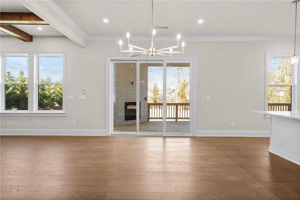 Spacious great room with hardwood floors, beamed ceiling, chandelier, gas fireplace, and sliding doors to deck in Davidson Homes The Arlington A, East Cobb, Georgia