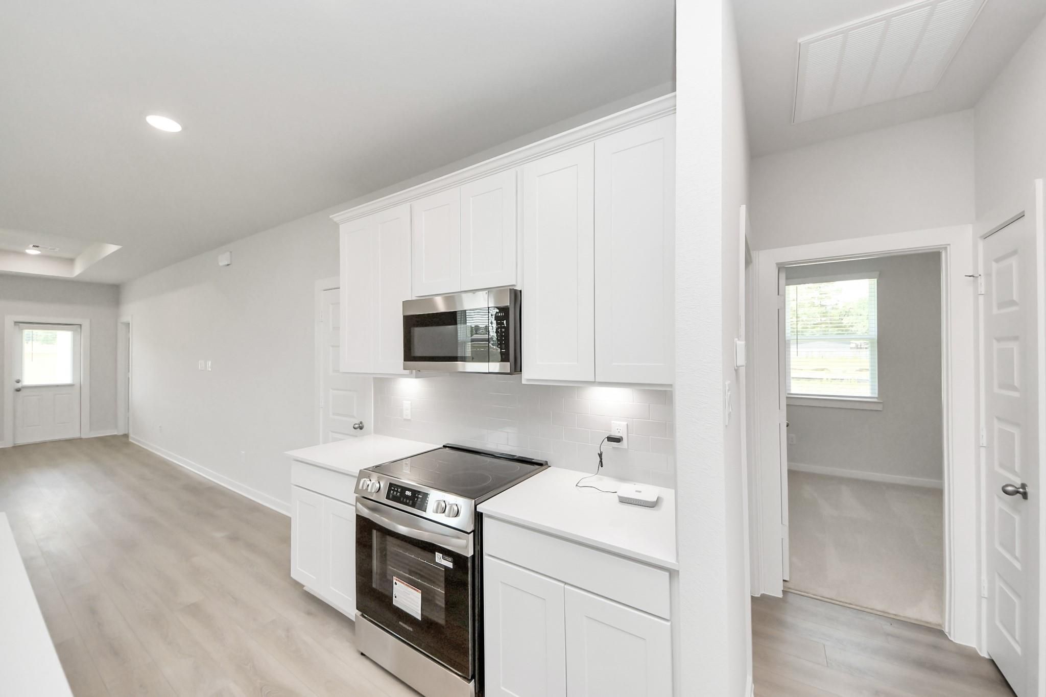 Modern kitchen with white cabinets and stainless appliances in The Frio F floor plan at Liberty Estates, Cleveland, Texas.