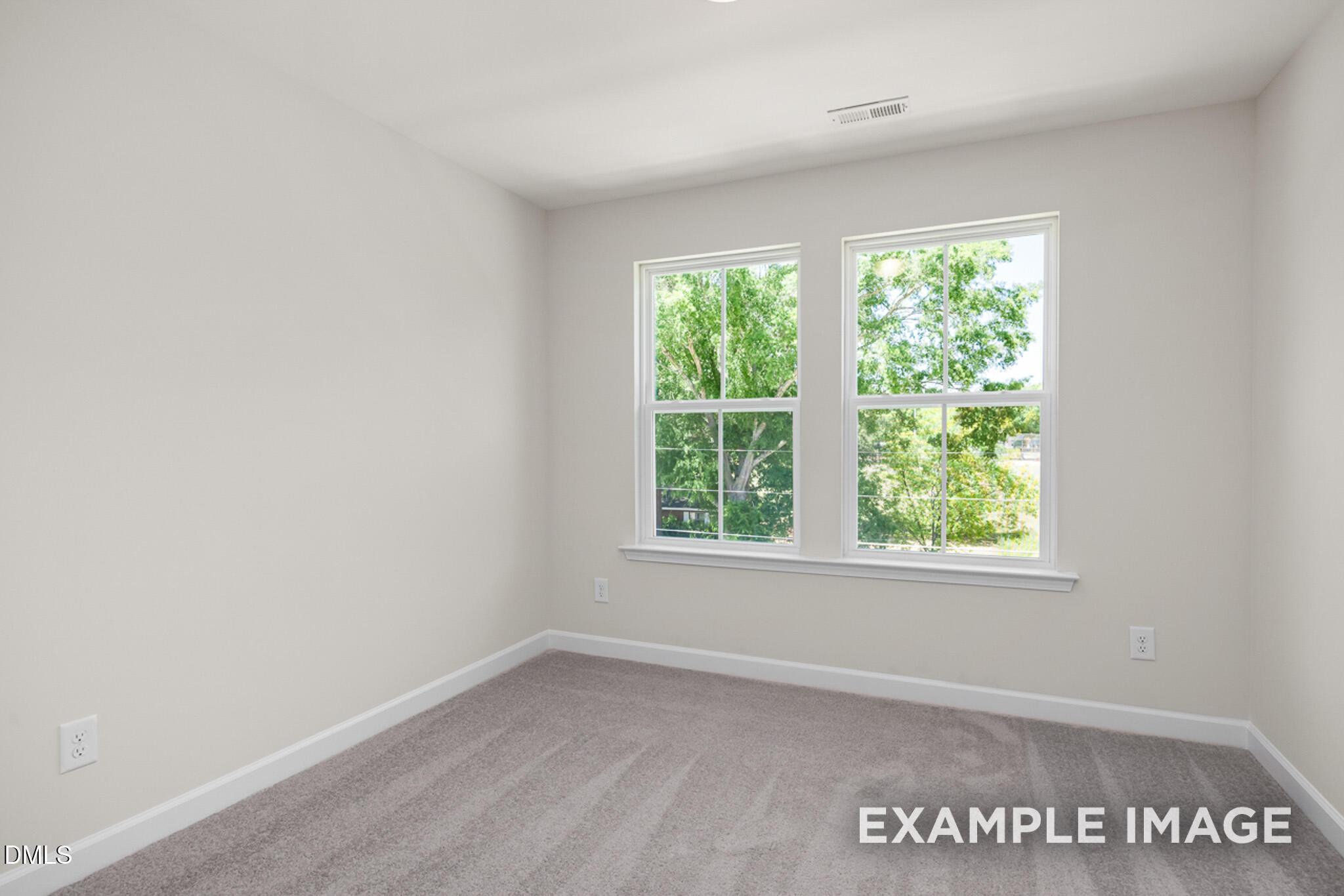 Bright, carpeted bedroom with large windows in The Mitchell Interior floor plan at Camden Park, Knightdale, North Carolina.