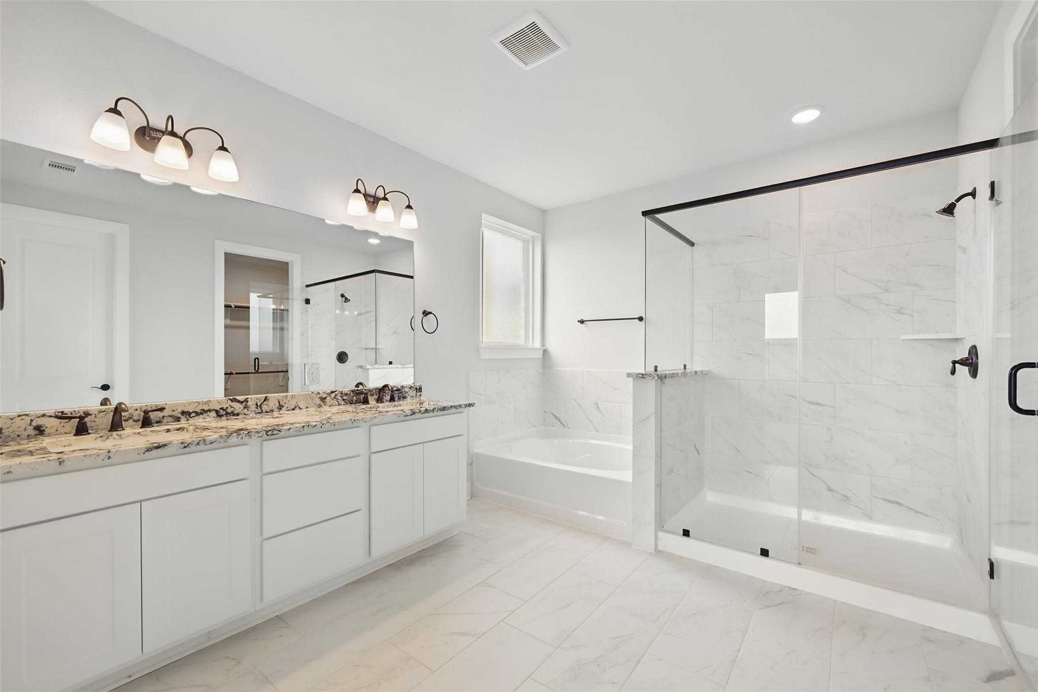 Elegant master bathroom featuring double vanity, granite countertop, soaking tub, and frameless glass shower in Davidson Homes The Victoria C