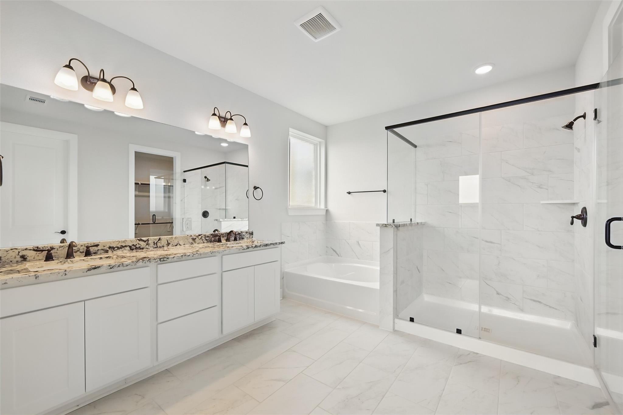 Elegant master bathroom featuring double vanity, granite countertop, soaking tub, and frameless glass shower in Davidson Homes The Victoria C