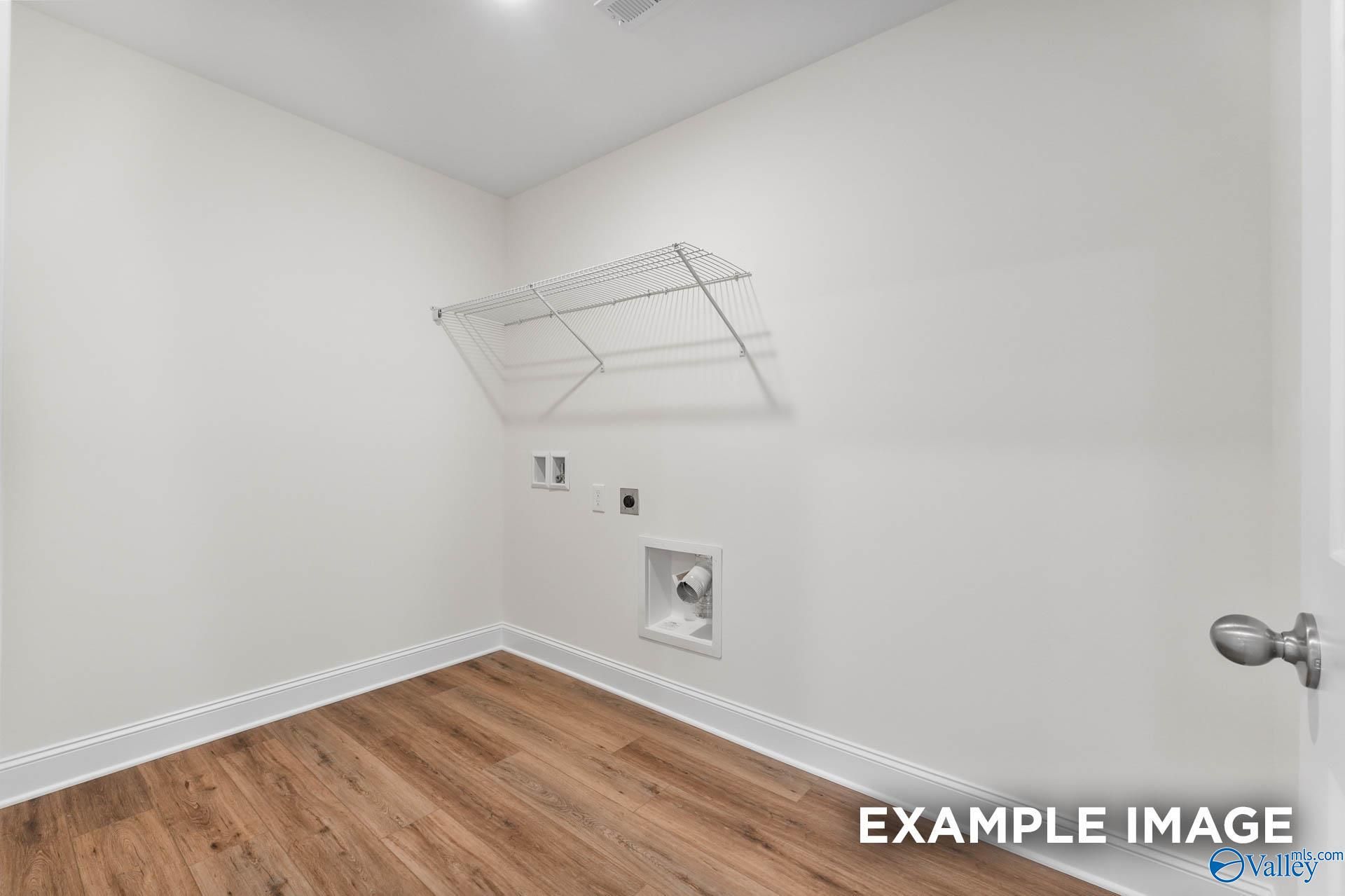 Bright laundry room with wire shelving, utility sink, washer/dryer hookups, and hardwood floors in Davidson Homes Shelby A, Hazel Green, Alabama