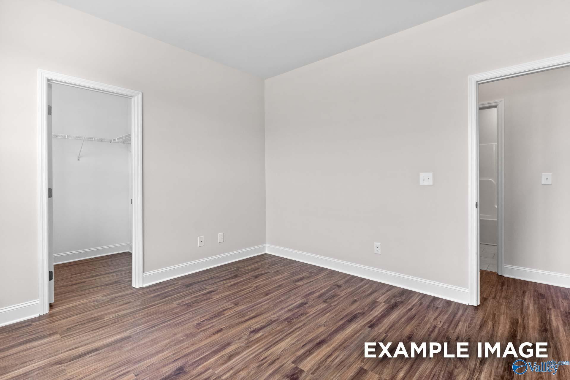 Bright bedroom with hardwood floors, walk-in closet, and adjacent bath in Davidson Homes The Montgomery C, Creekside, Harvest, AL