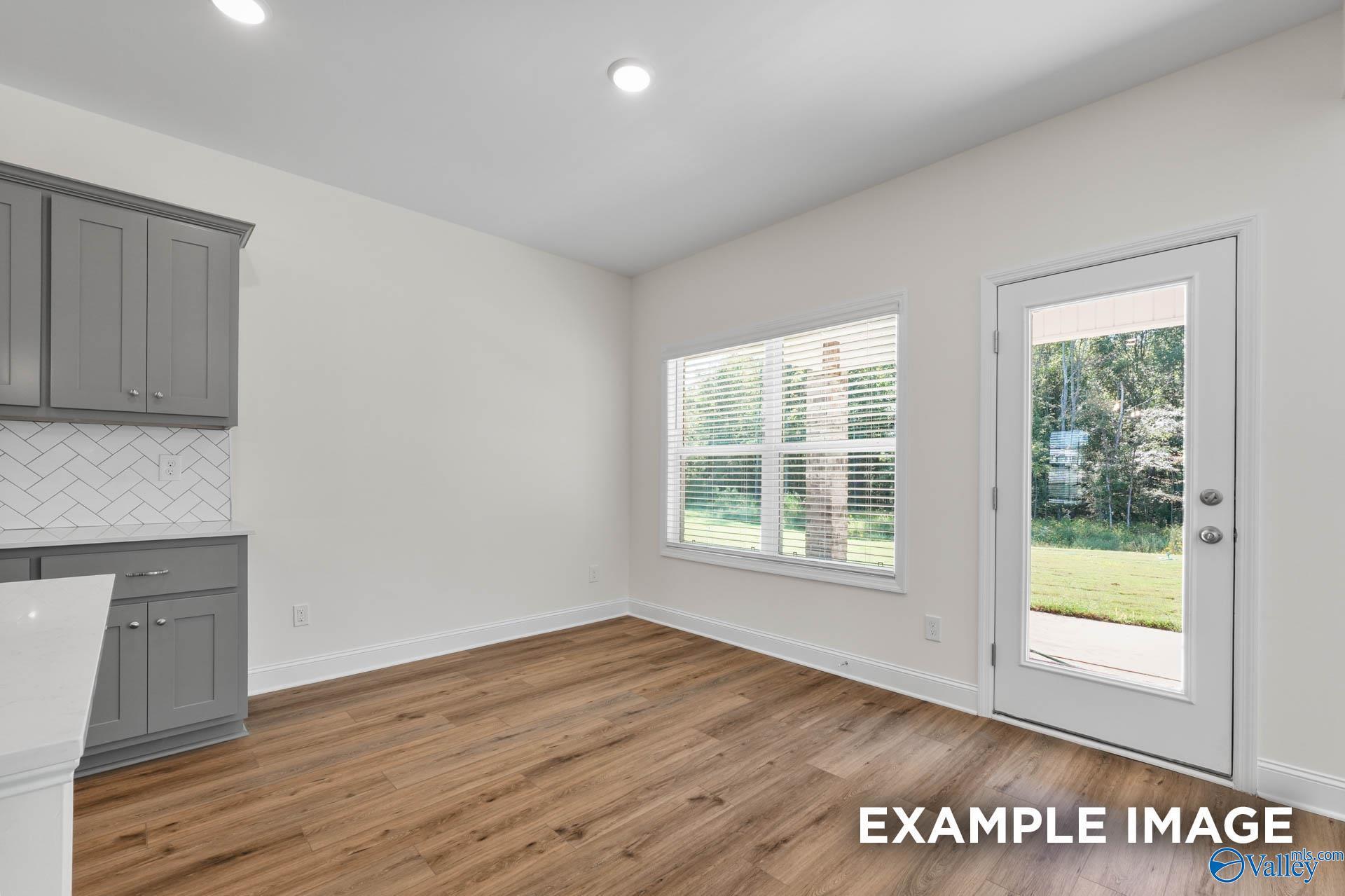 Bright kitchen with gray shaker cabinets, subway tile backsplash, and glass door to green backyard in Davidson Homes The Shelby A, Hazel Green, AL
