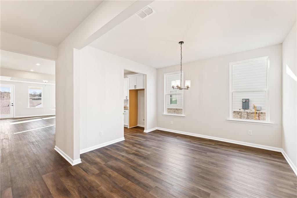 Bright dining room with hardwood floors, chandelier, and arched entry in The Glenwood A 3-bedroom home, Kelly Preserve, Loganville, GA