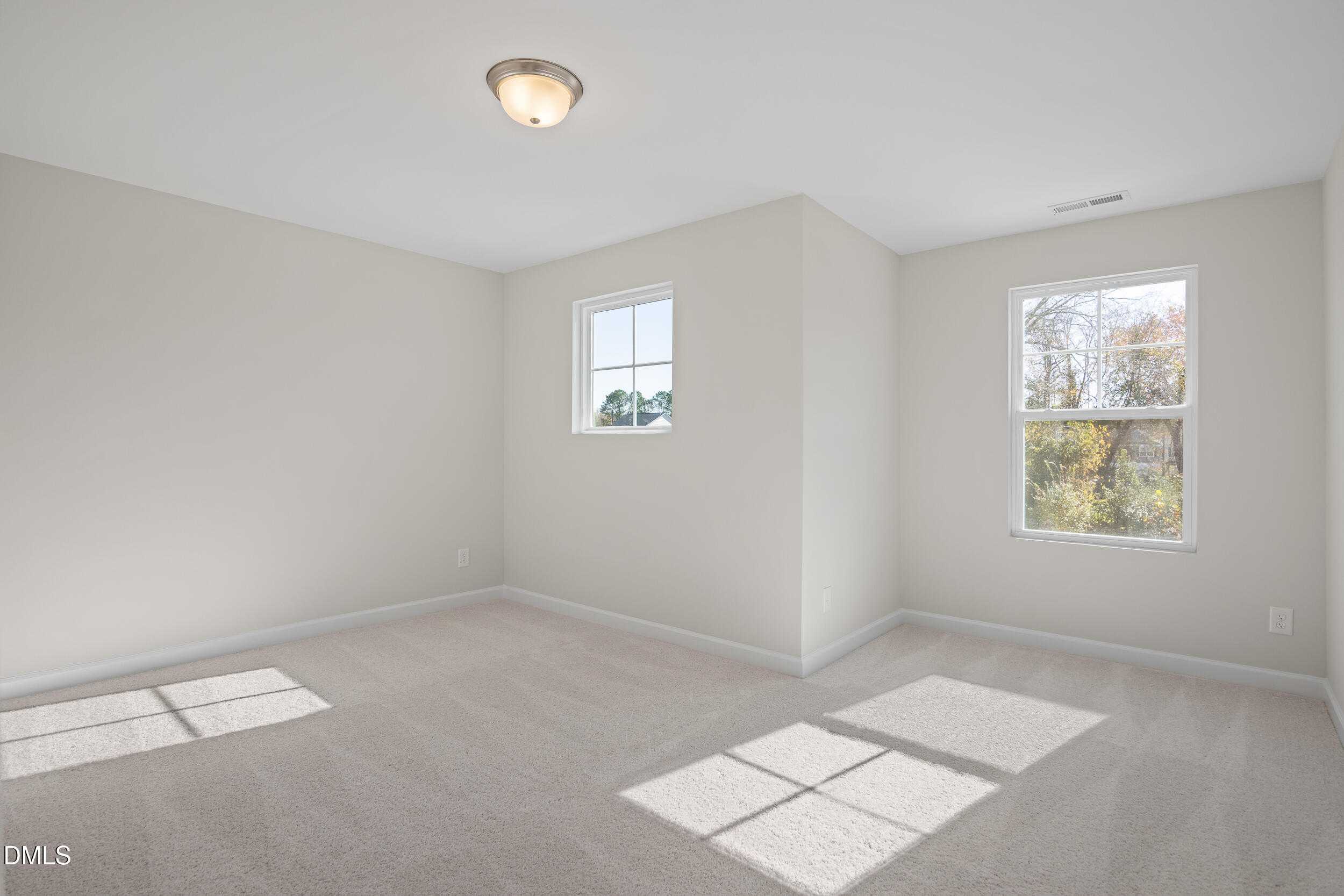 Bright secondary bedroom with beige carpet, light gray walls, and sunny windows in Davidson Homes The Preston C, Lillington, NC
