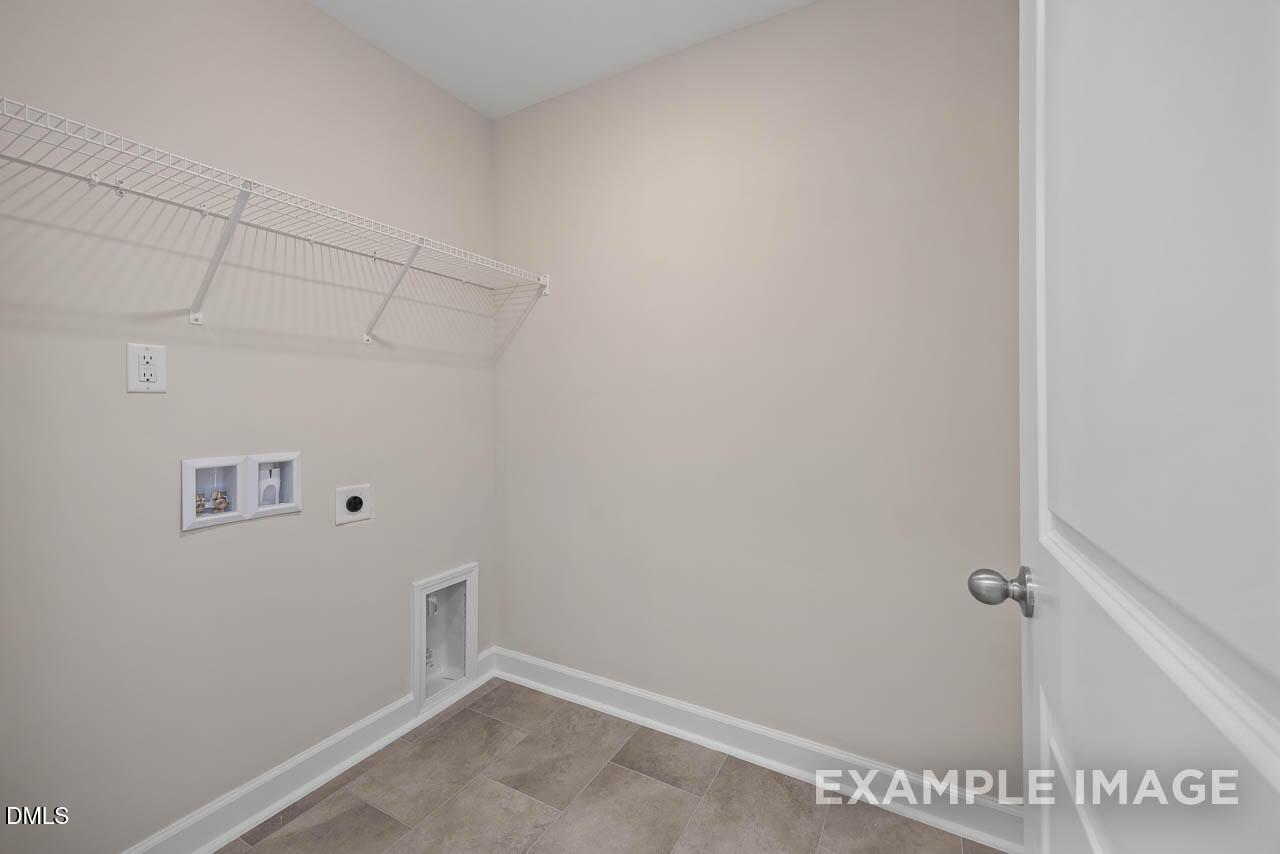 Functional laundry room with wire shelving, washer-dryer hookups, and beige walls in Davidson Homes The Graham 3-bedroom, Fuquay-Varina, NC
