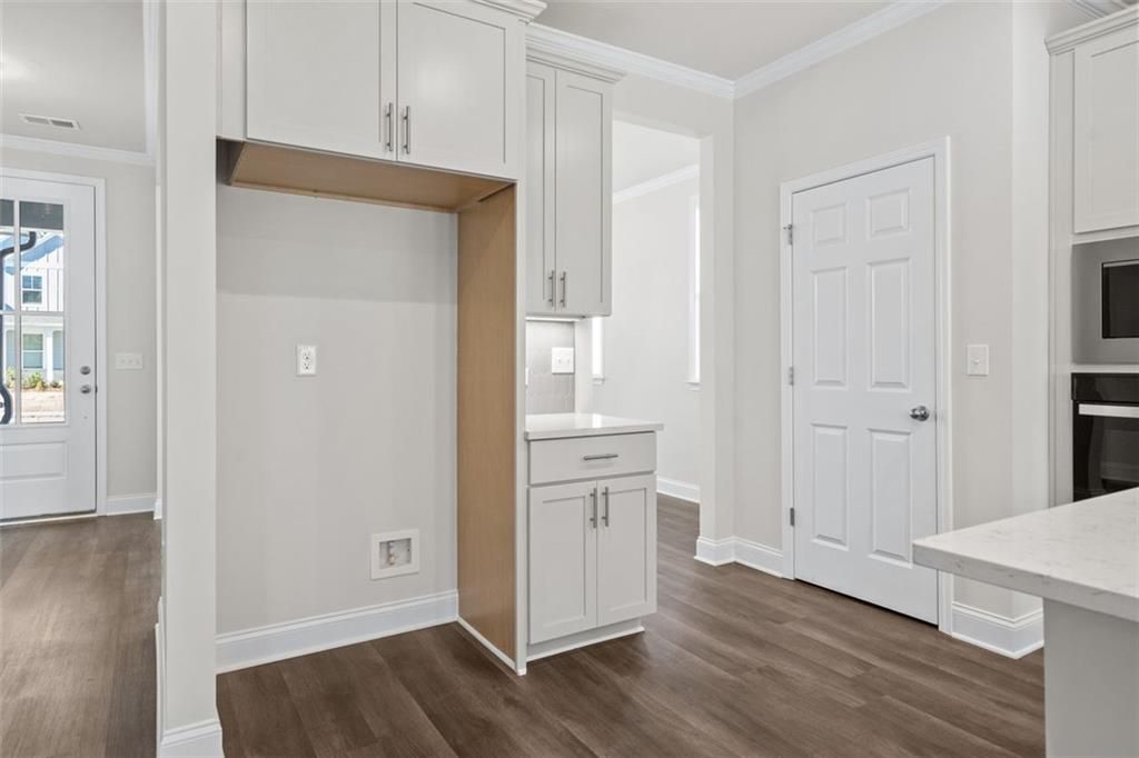 Contemporary kitchen with white shaker cabinets, quartz counters, and stainless appliances in Davidson Homes The Ash C at Wehunt Meadows, Hoschton