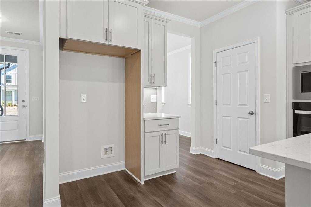 Contemporary kitchen with white shaker cabinets, quartz counters, and stainless appliances in Davidson Homes The Ash C at Wehunt Meadows, Hoschton