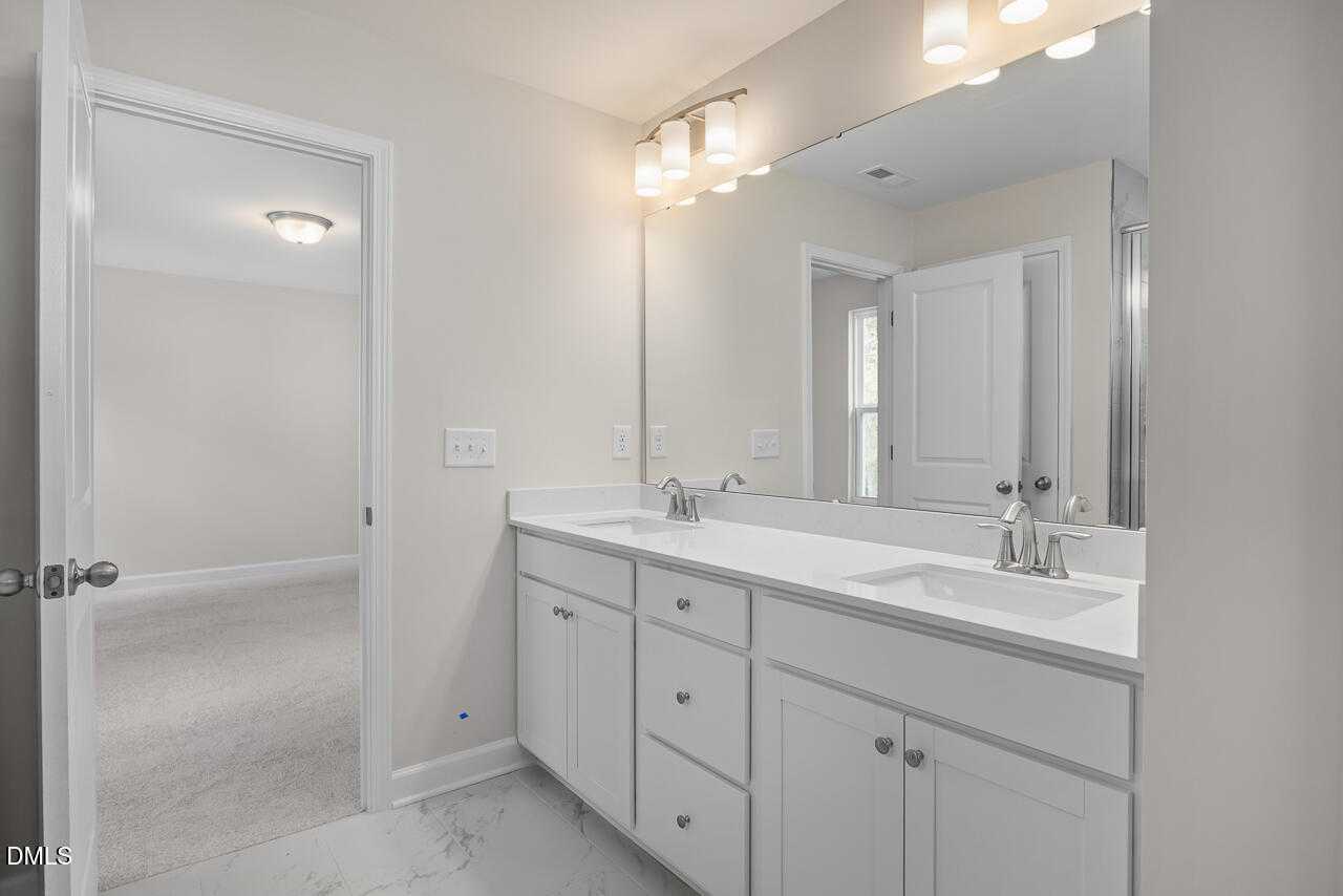 Modern master bathroom with double white vanity, quartz counters, and frameless shower in Davidson Homes The Gavin C, Lillington, NC
