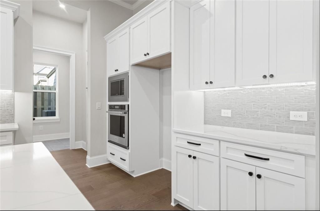 Modern white shaker kitchen with quartz counters, double ovens, subway backsplash in Davidson Homes Seaside A, Woodstock GA