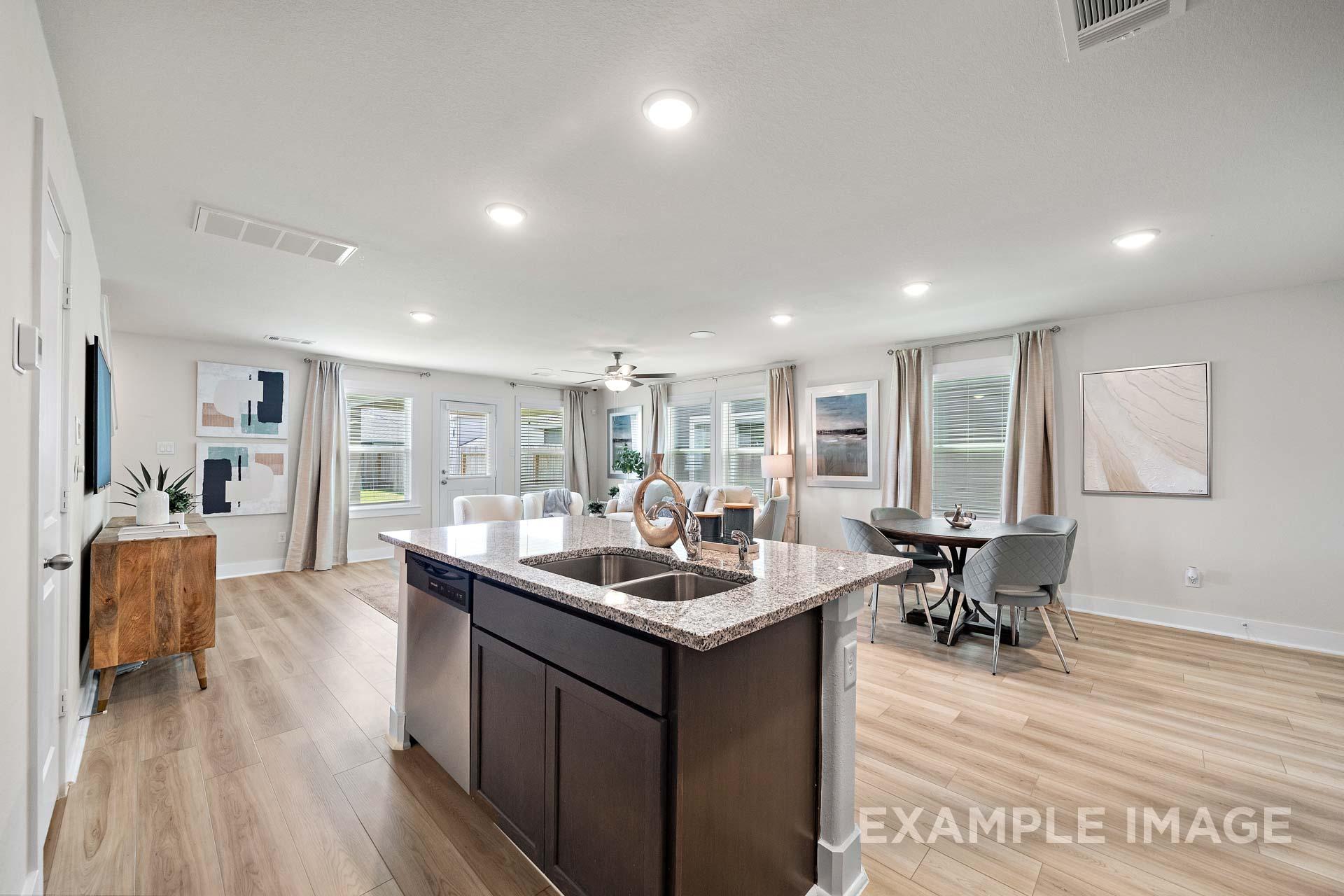 Open-concept kitchen and living area in The Lily A Davidson Homes floor plan with granite island, dining nook, and large windows