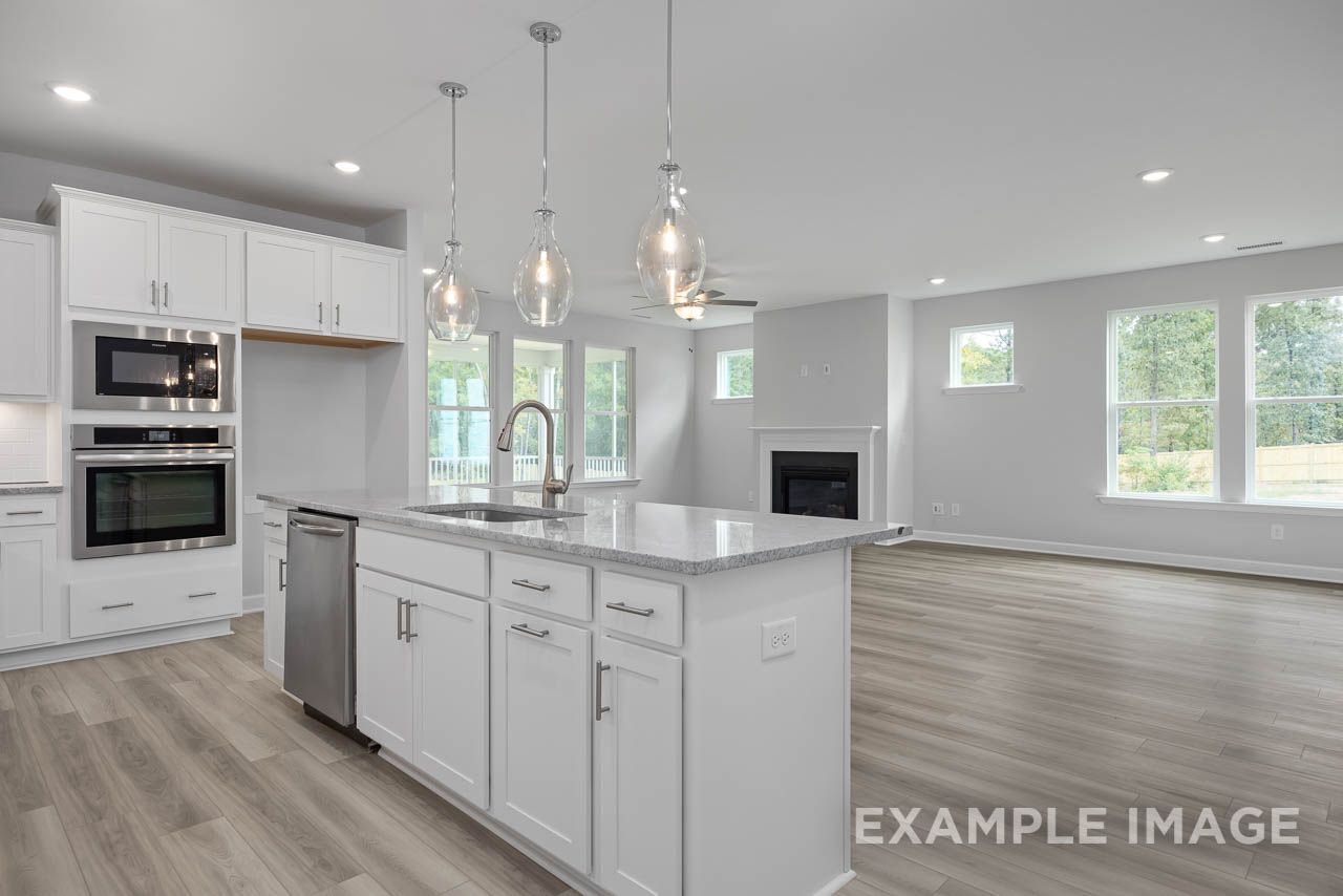 Open-concept kitchen and living area at Retreat at North Main in Lillington, NC by Davidson Homes with white cabinetry.