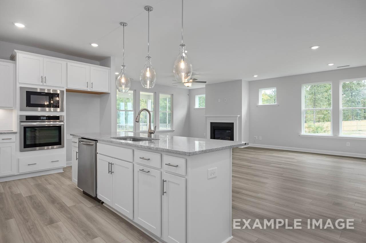Open-concept kitchen and living area at Retreat at North Main in Lillington, NC by Davidson Homes with white cabinetry.