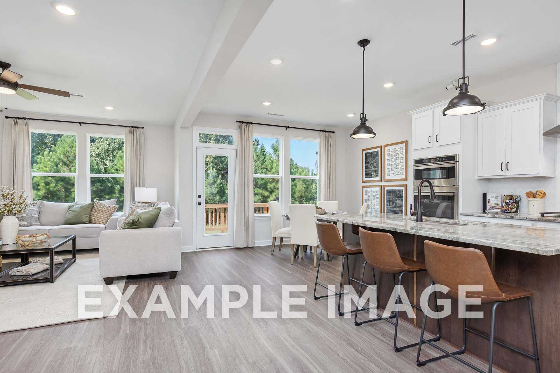 Open-concept kitchen and living room in The Willow home design by Davidson Homes, with white cabinetry, quartz island, and large windows