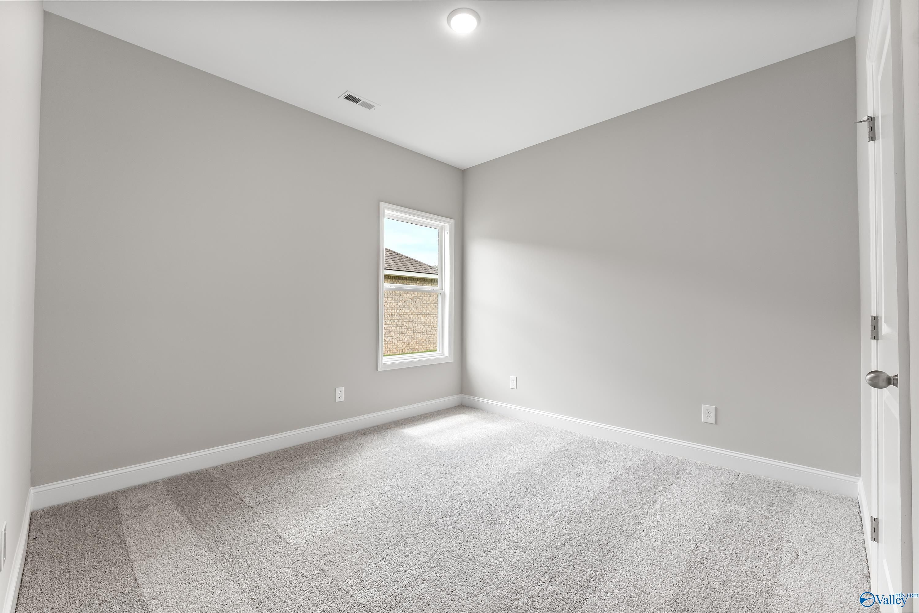 Bright secondary bedroom with light gray walls, large window, and carpeted floor in Davidson Homes The Franklin C, Huntsville AL