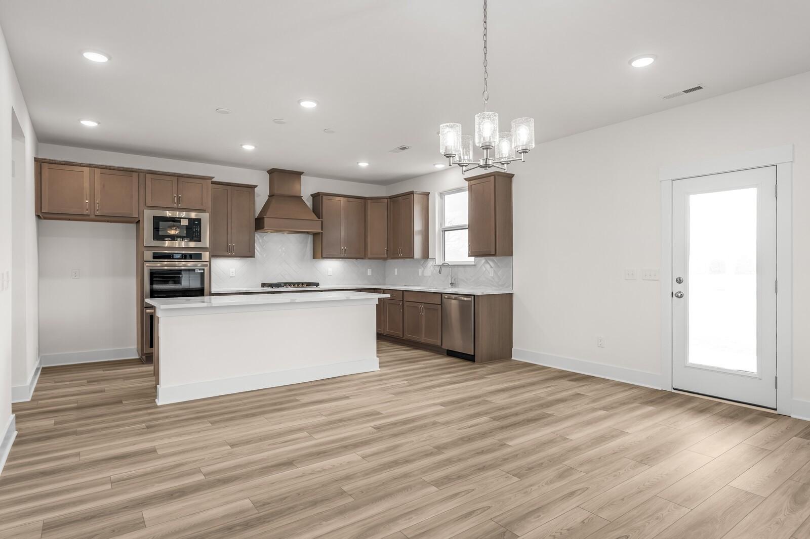 Modern kitchen with white island, wood cabinets, and stainless appliances in The Henry C floor plan, Benders Cove, Mt. Juliet.