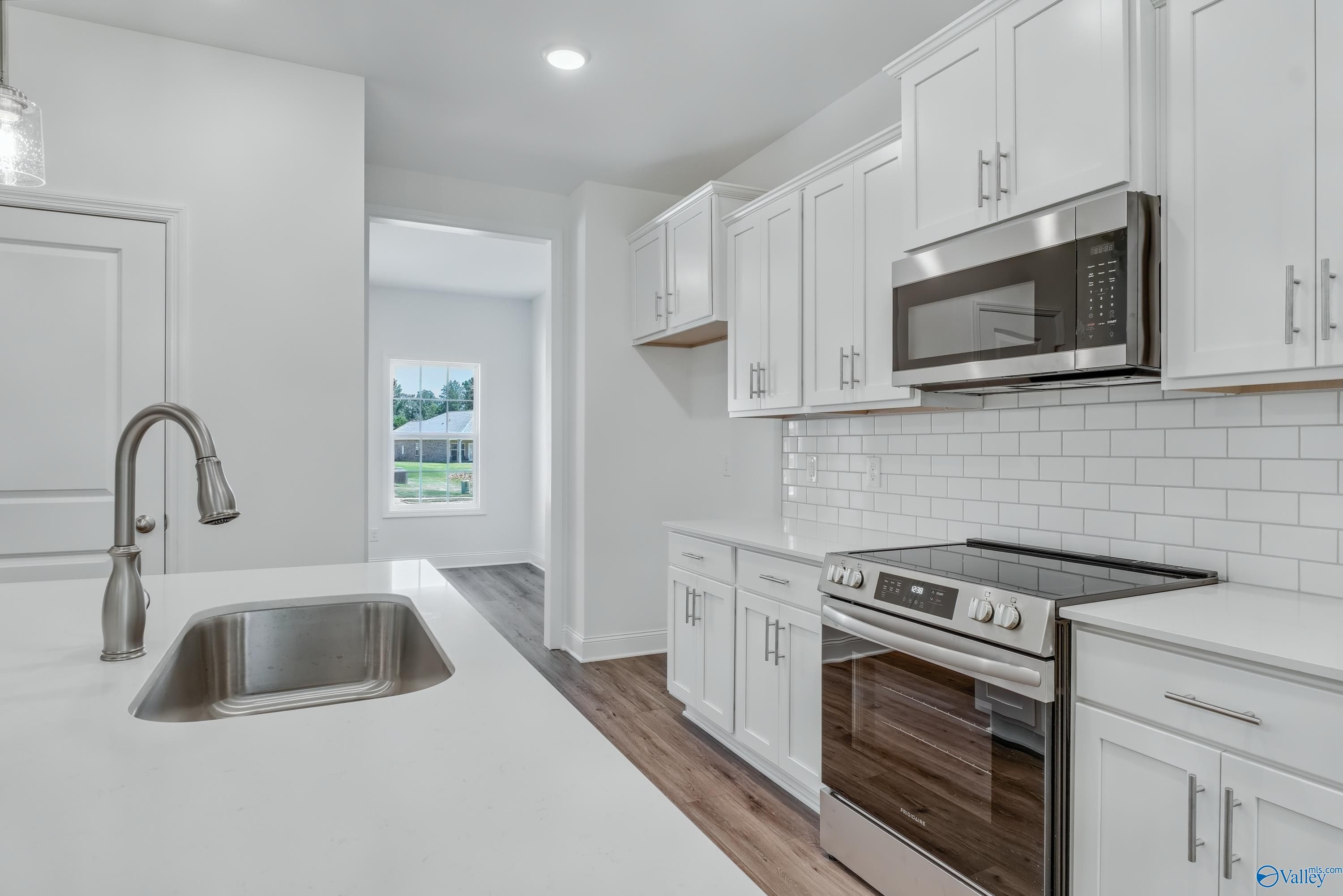 Modern white kitchen with stainless appliances, subway tile backsplash, and island sink in The Shelby A, Davidson Homes, Arab, Alabama