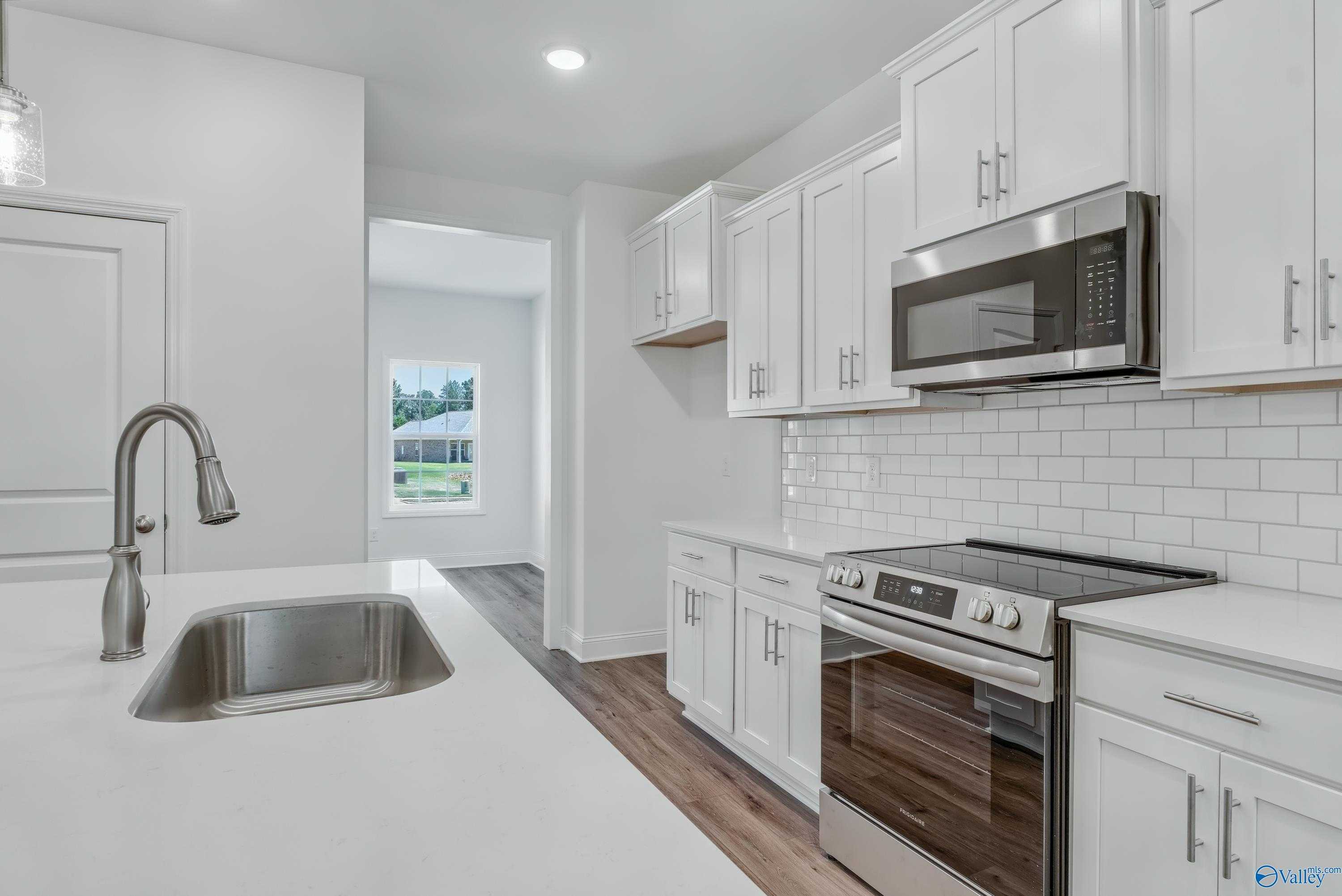 Modern white kitchen with stainless appliances, subway tile backsplash, and island sink in The Shelby A, Davidson Homes, Arab, Alabama