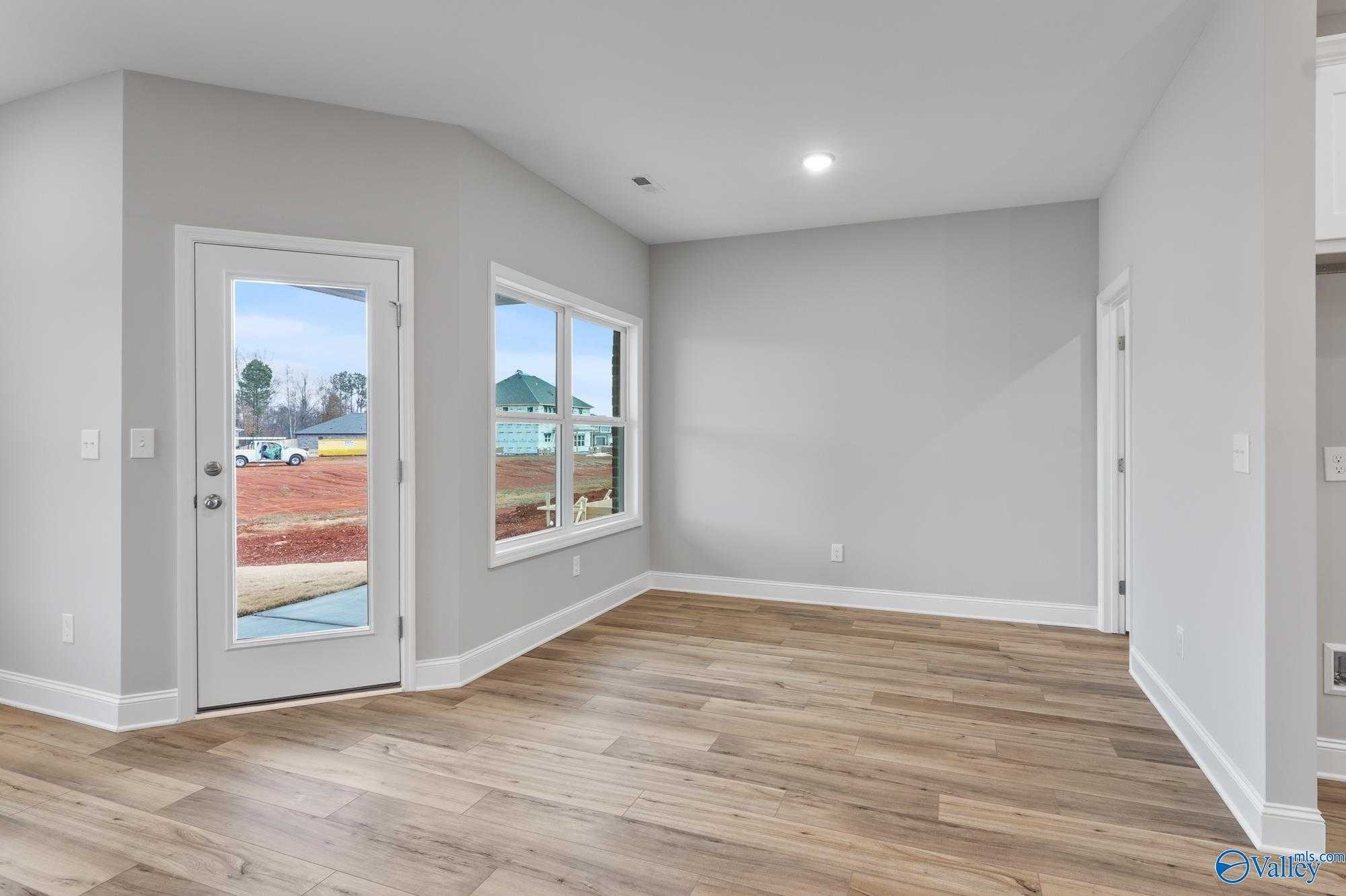 Bright flex room featuring hardwood floors, large windows, and glass door to backyard view in Davidson Homes The Daphne D, Athens AL