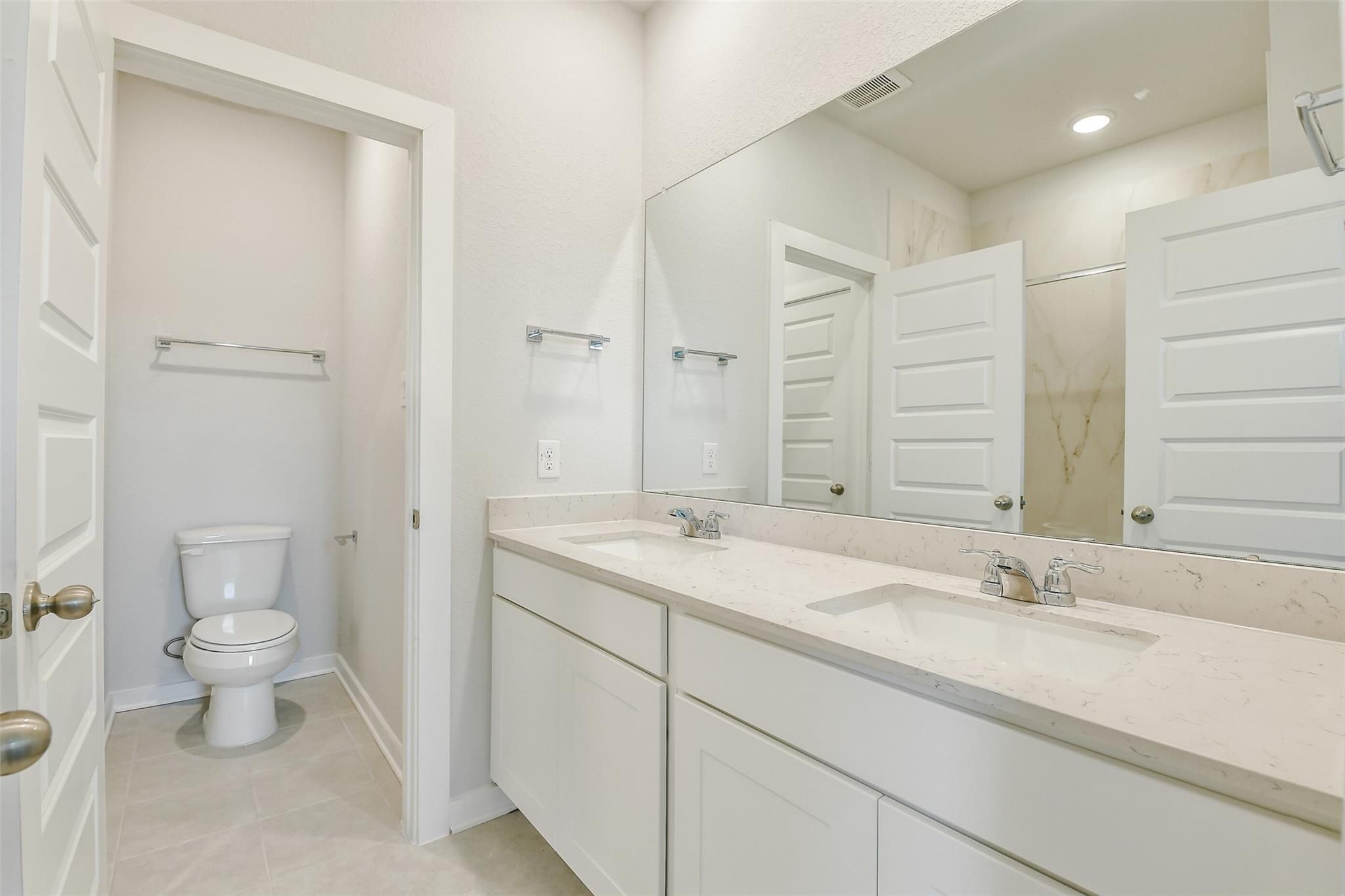 Modern master bathroom featuring double vanity, walk-in shower, and large mirror in Davidson Homes The Colorado F, Cleveland, Texas