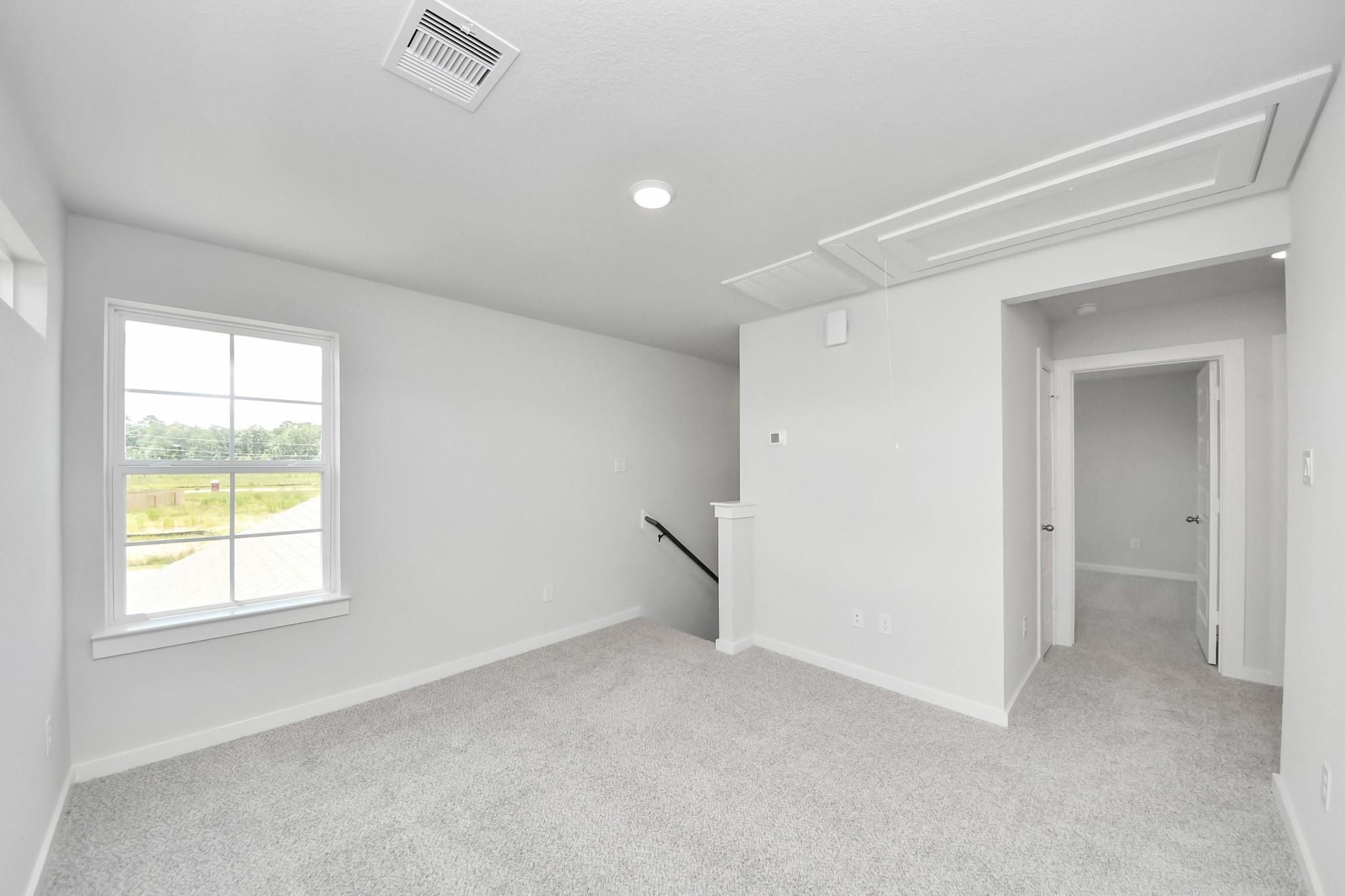Bright carpeted second-floor loft with staircase access in The Sabine F floor plan by Davidson Homes in Cleveland, Texas.