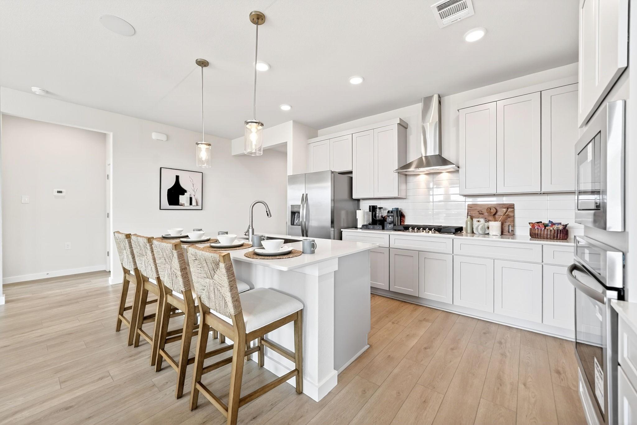 Modern kitchen with white cabinets, island seating, and stainless appliances in The Laurel O plan at Parks at Foster Crossing.