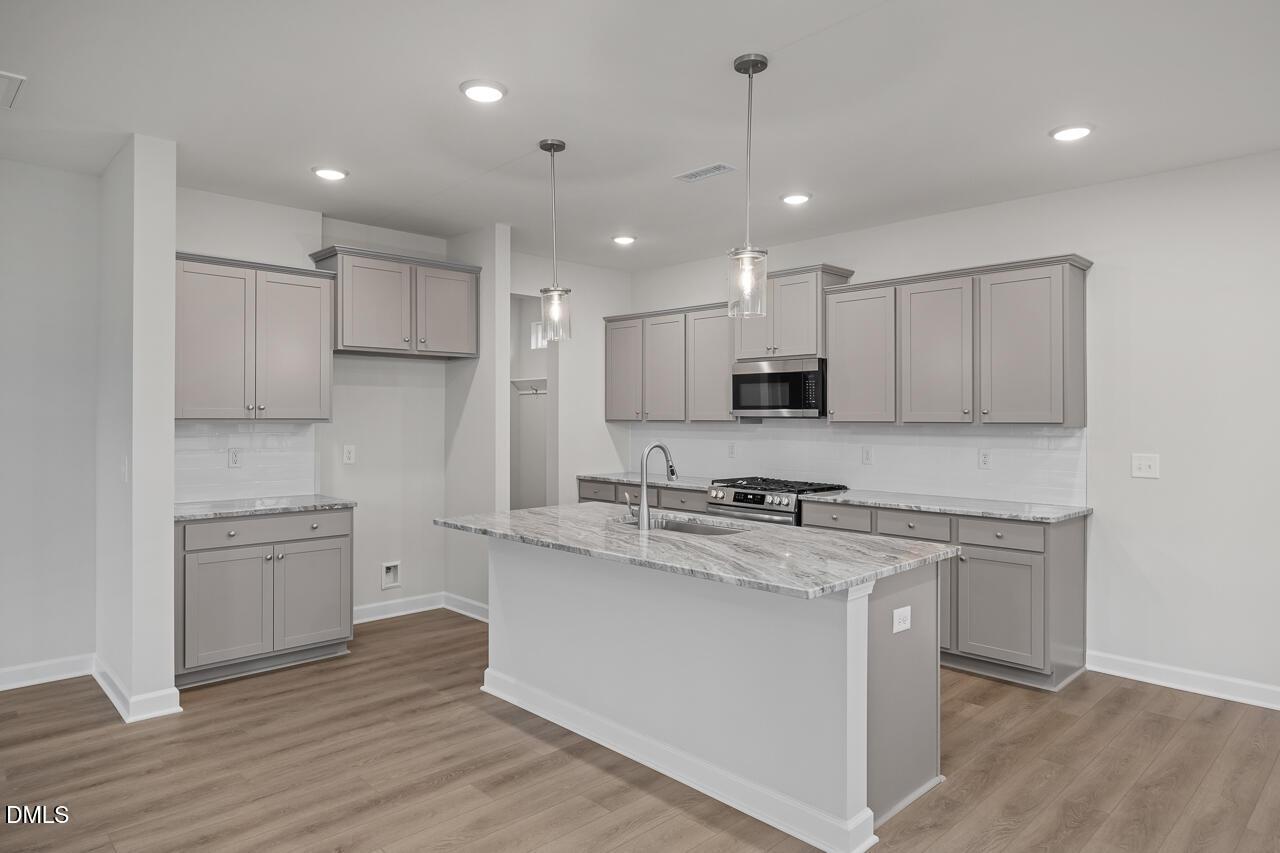 Modern kitchen with gray shaker cabinets, white quartz island sink, stainless steel appliances in The Gavin B, Lillington, NC