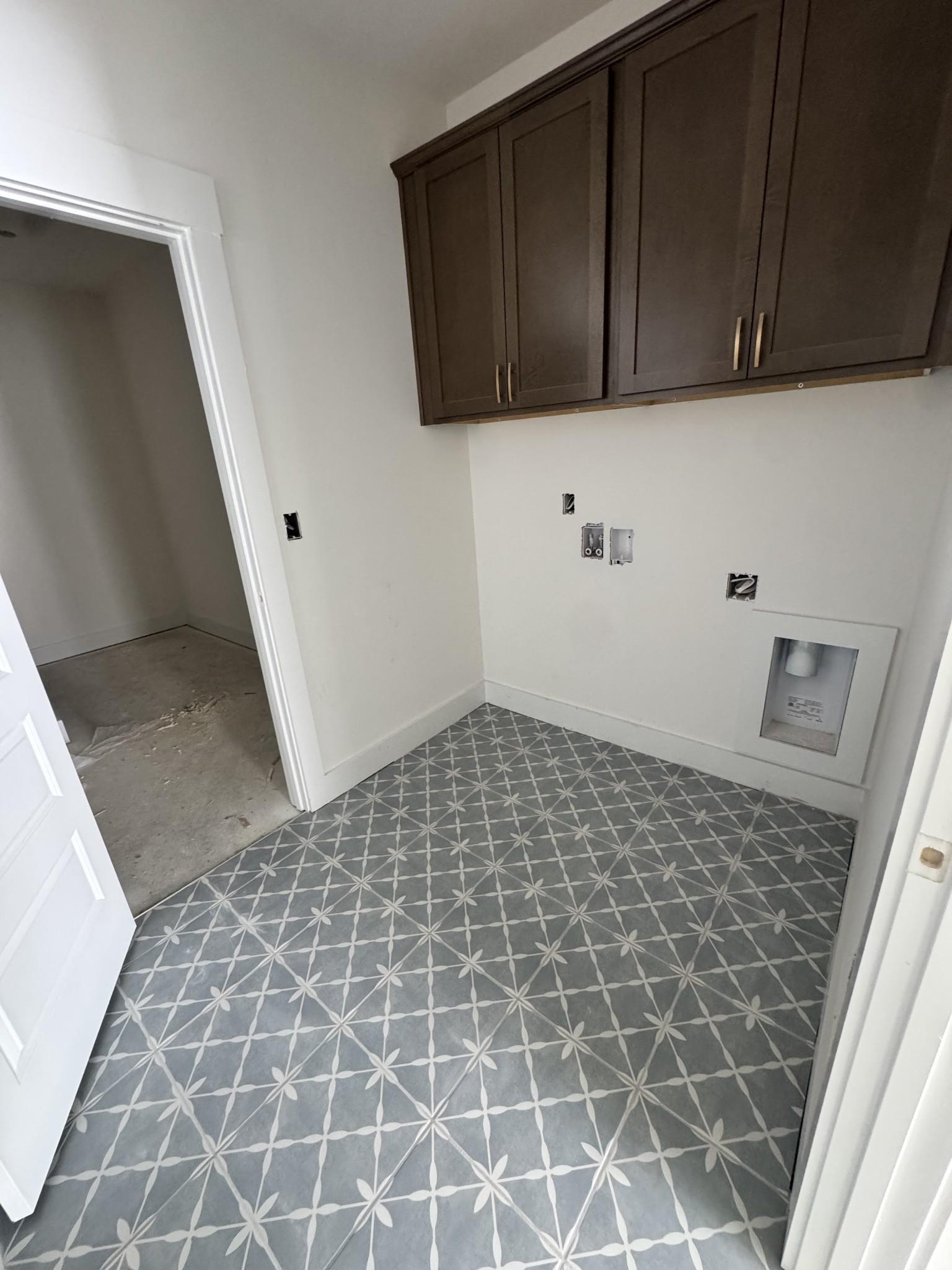 Laundry room with patterned tile floors and dark wood cabinets in The Prairie C floor plan at Woods Crossing, Gallatin.