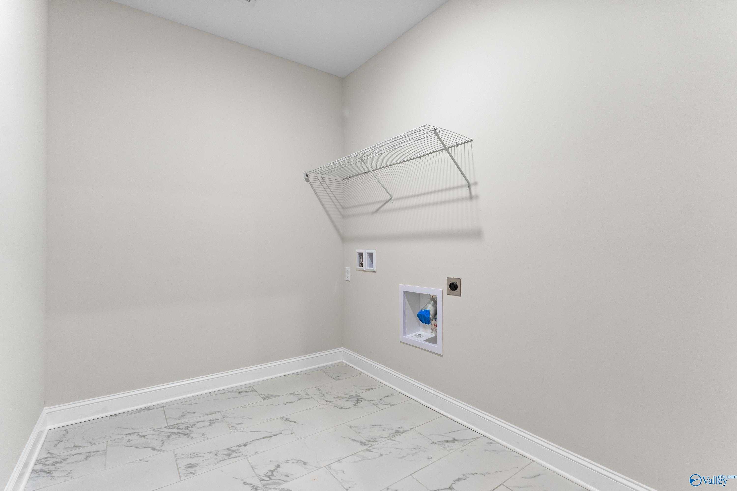 Spacious laundry room with wire shelving, utility sink and marble-look tile floor in Davidson Homes The Finleigh, Toney, Alabama